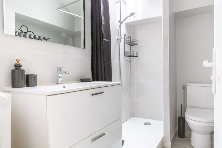 Salle d'eau blanche avec douche et meuble vasque
