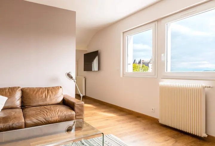 Salon lumineux avec canapé en cuir et grandes fenêtres, appartement à Pau