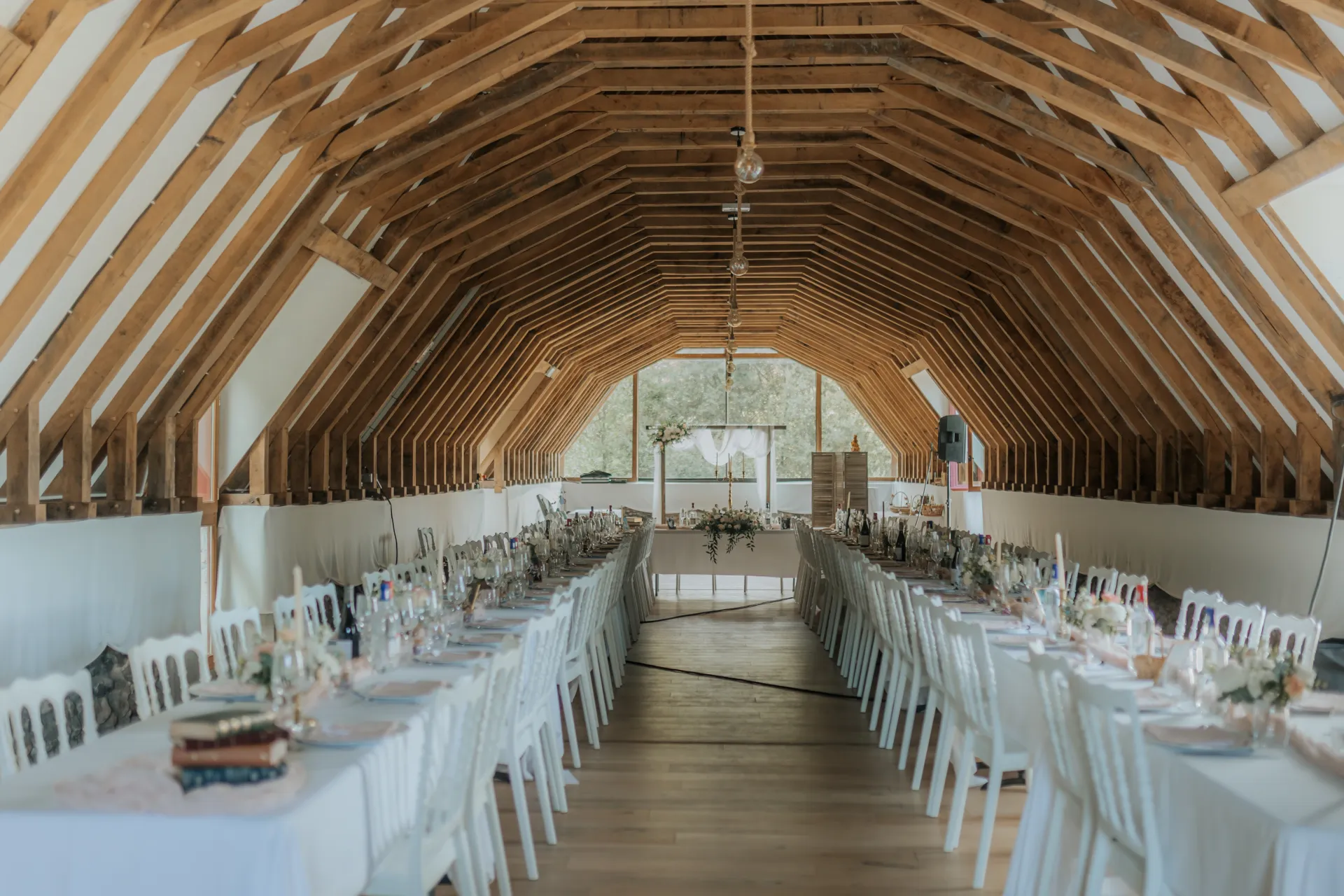 Salle de réception de mariage à Pau dans les Pyrénées-Atlantiques, avec charpente en bois et longues tables dressées