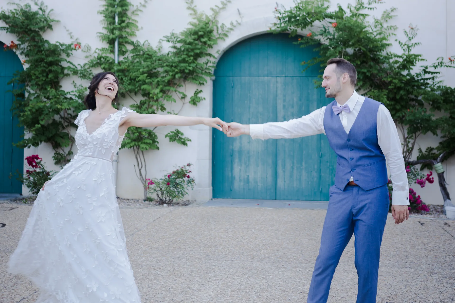 Couple de mariés dansant devant une bâtisse aux portes bleues, lieu de mariage romantique à Pau, Pyrénées-Atlantiques
