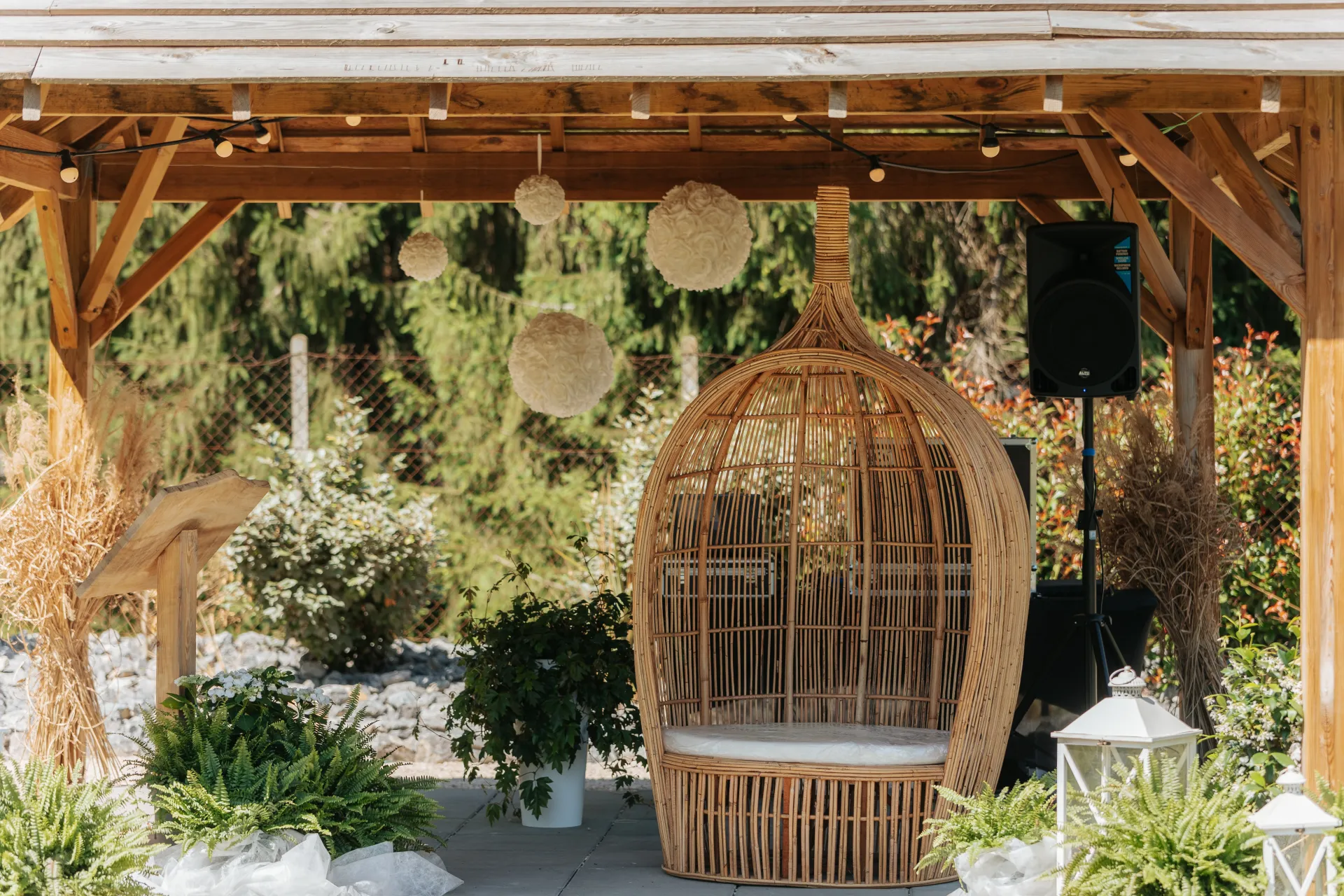 Espace de cérémonie de mariage à Pau sous un pavillon en bois, avec fauteuil en rotin et décoration bohème