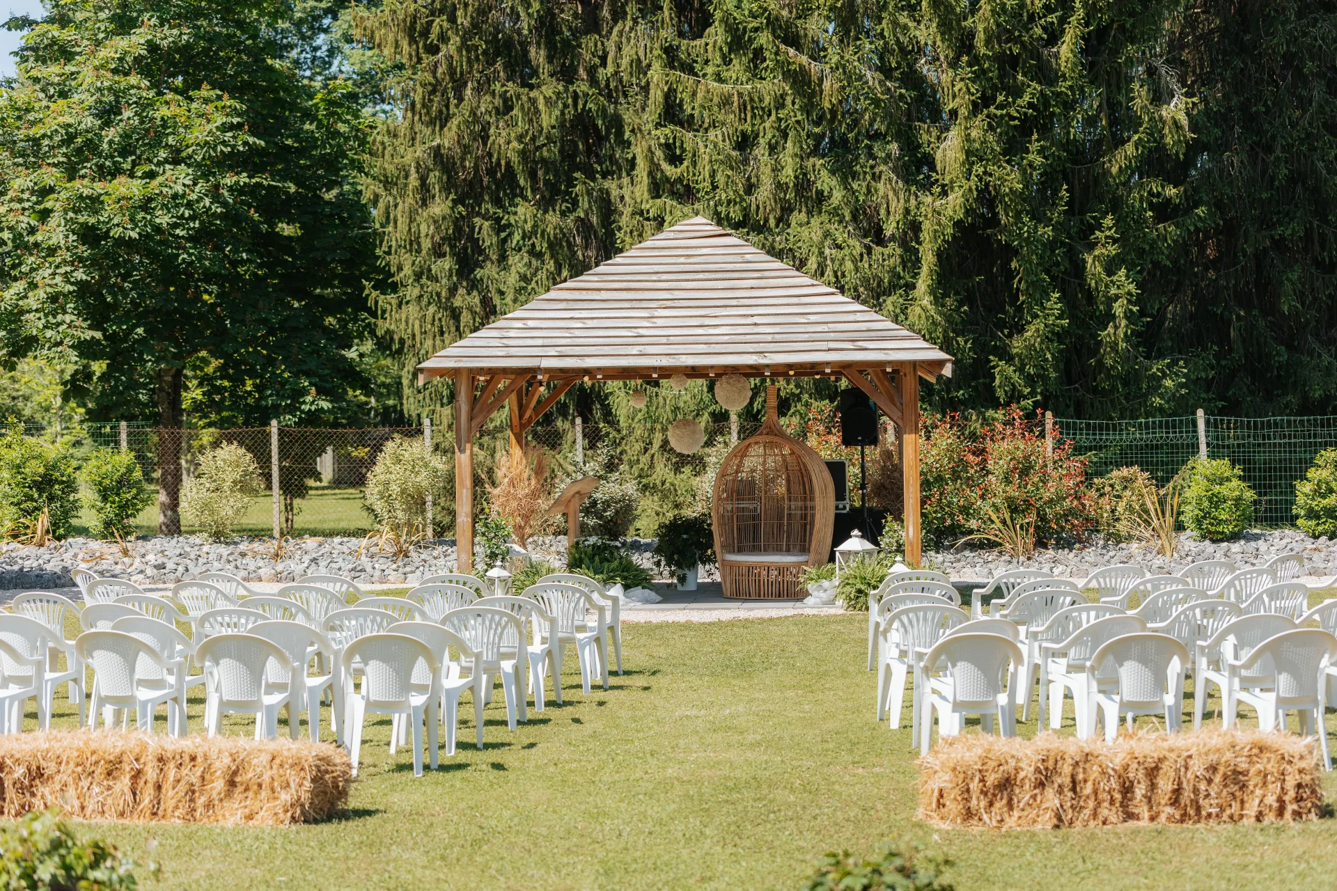 Cérémonie laïque de mariage en plein air près de Pau, avec arche en bois, chaises blanches et jardin arboré