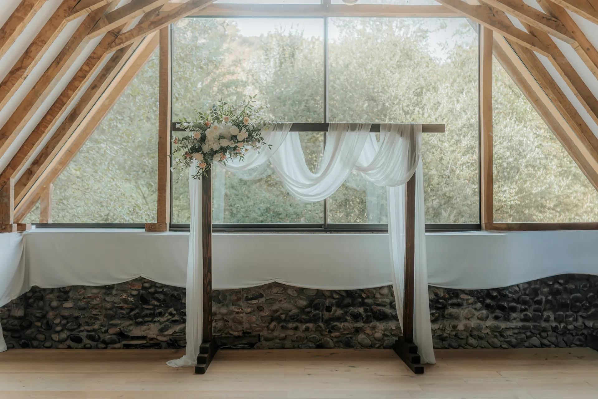 Arche de cérémonie de mariage fleurie dans une salle lumineuse à Pau, lieu de réception élégant en Pyrénées-Atlantiques