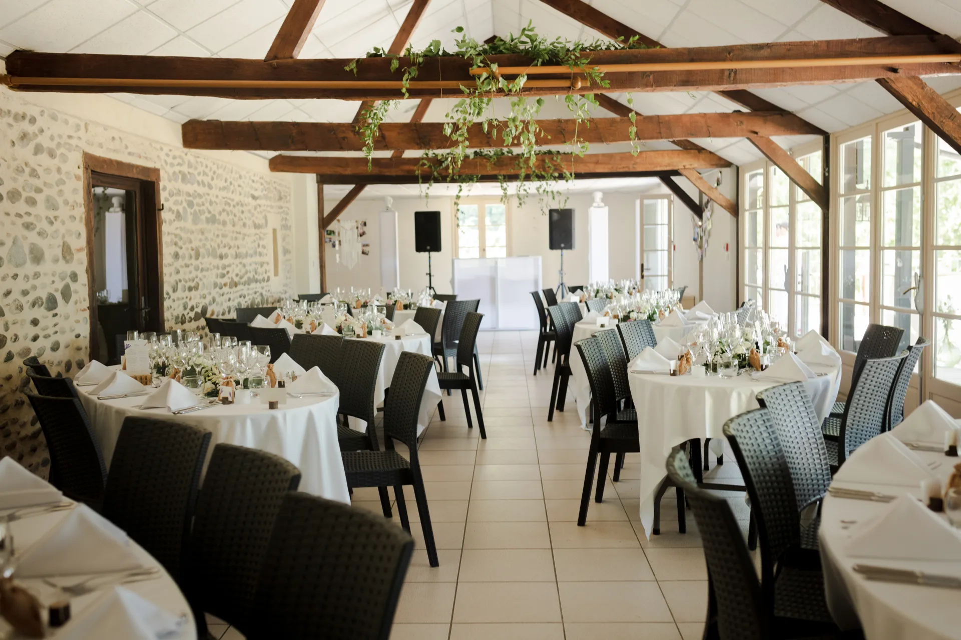 Salle de réception de mariage lumineuse à Pau, décorée avec tables rondes, poutres en bois et ambiance élégante