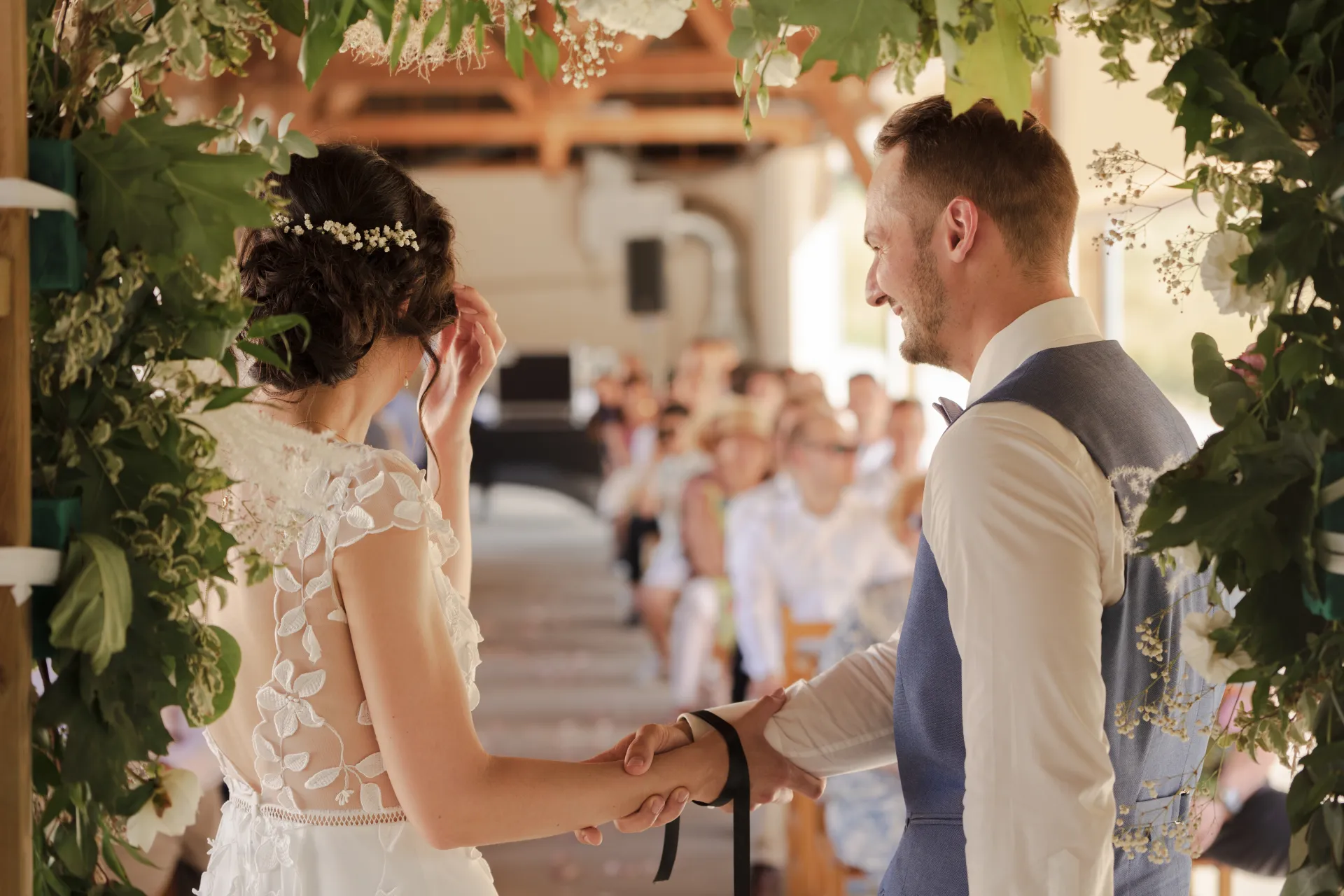 Mariés échangeant leurs vœux sous une arche fleurie lors d’un mariage à Pau, dans les Pyrénées-Atlantiques