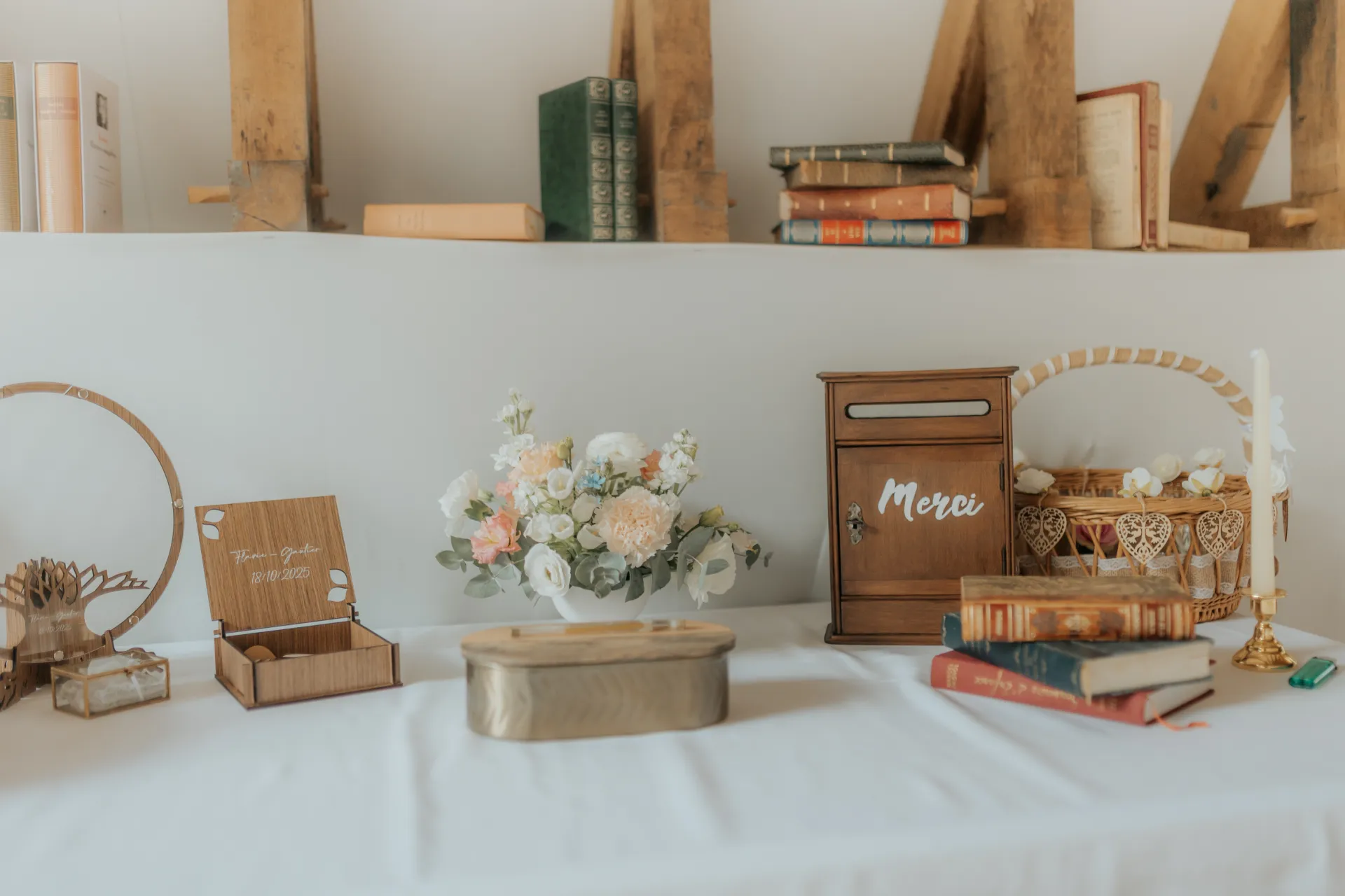 Décoration de mariage élégante à Pau : urne Merci, fleurs pastel et livres anciens sur une table de réception