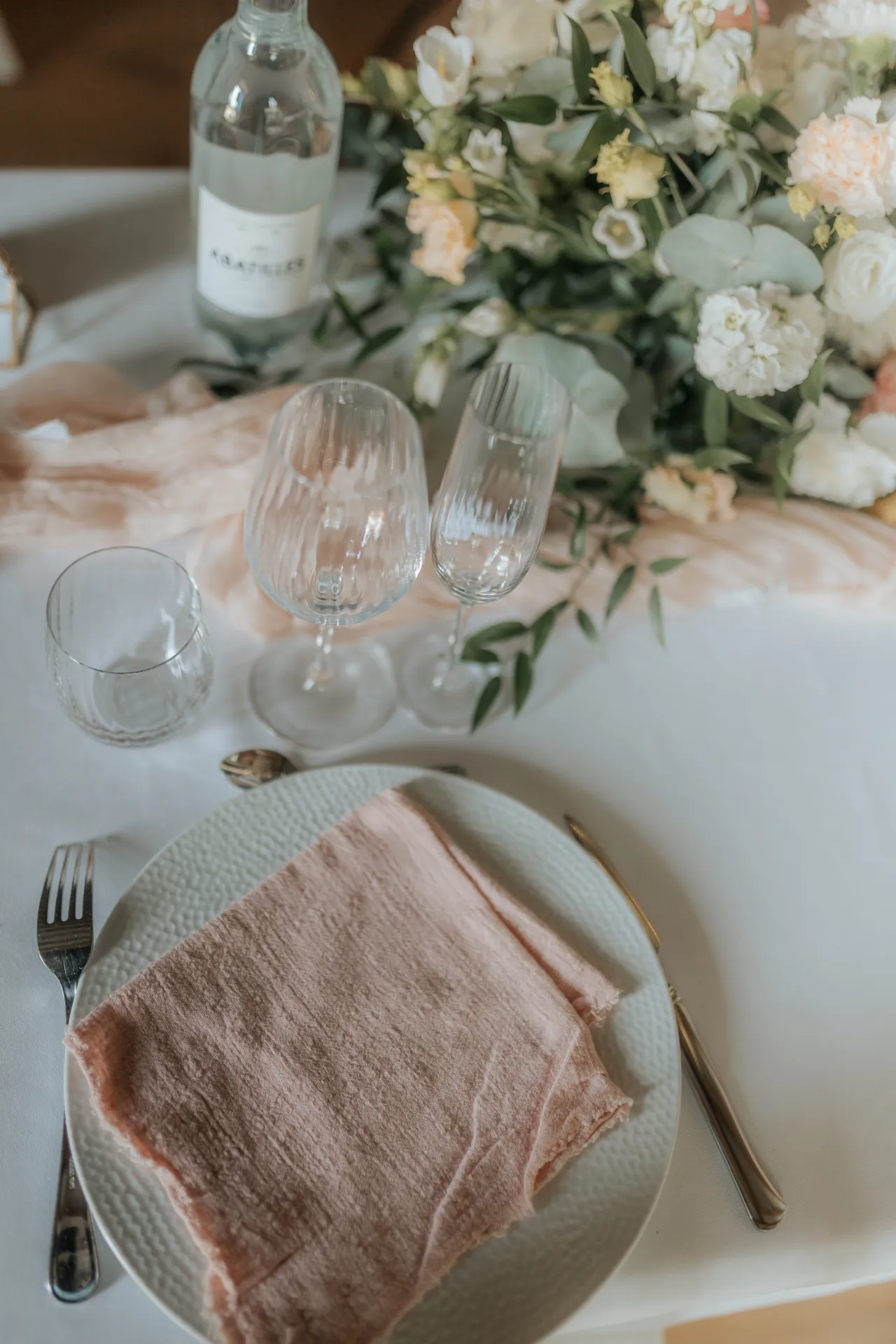 Table de mariage élégante à Pau avec fleurs pastel, verres ciselés et serviette rose poudré