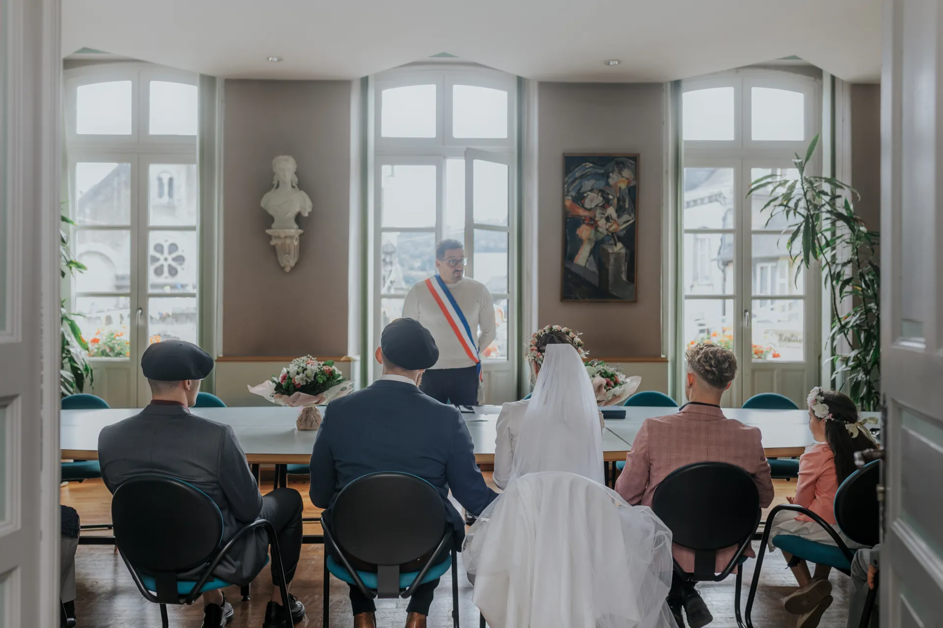 Cérémonie de mariage intimiste à la mairie d’Arudy, mariés et proches assis face à l’officiant dans une salle lumineuse