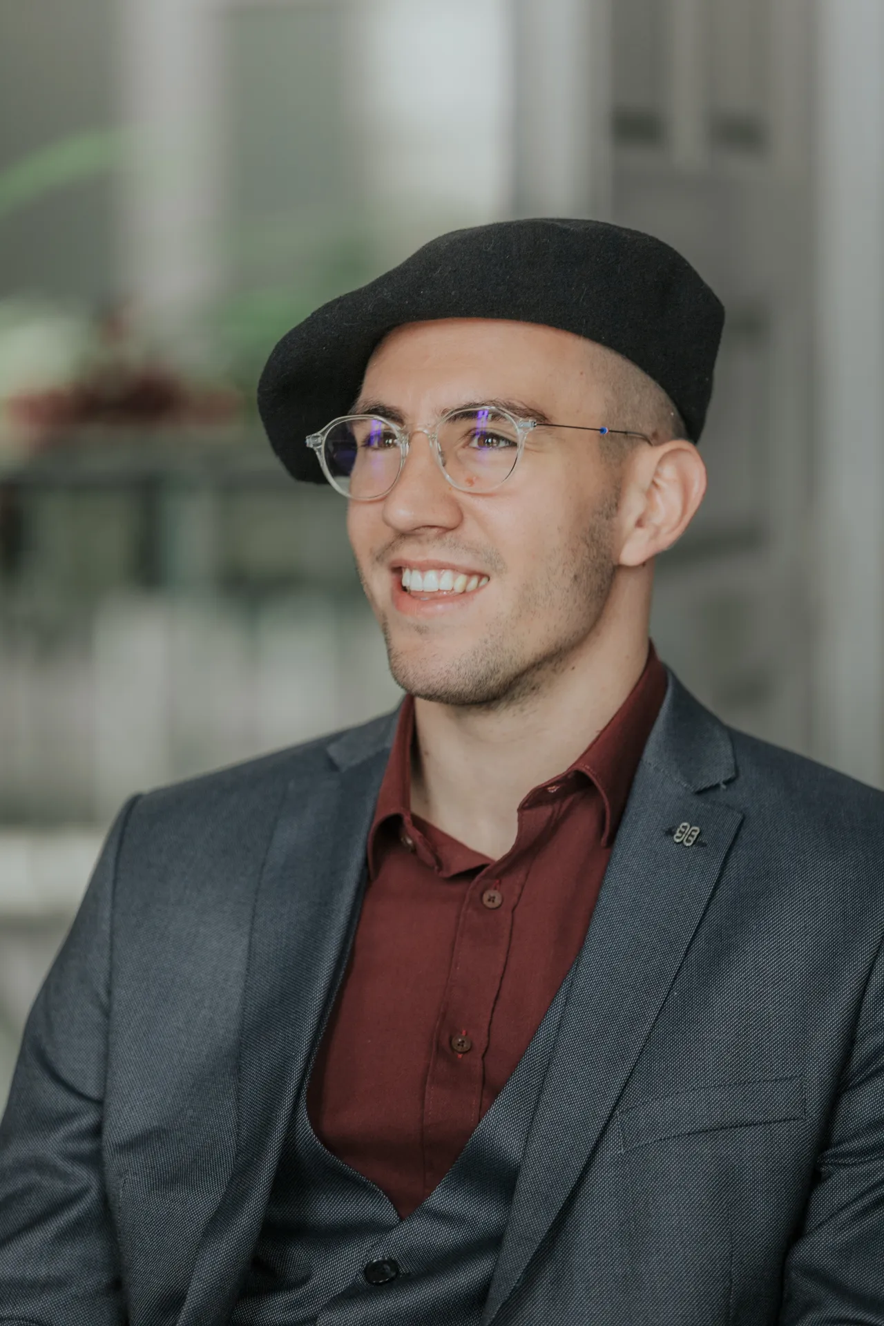Portrait du marié souriant à la mairie d’Arudy, en costume gris, lunettes et béret noir, lors d’un mariage intimiste