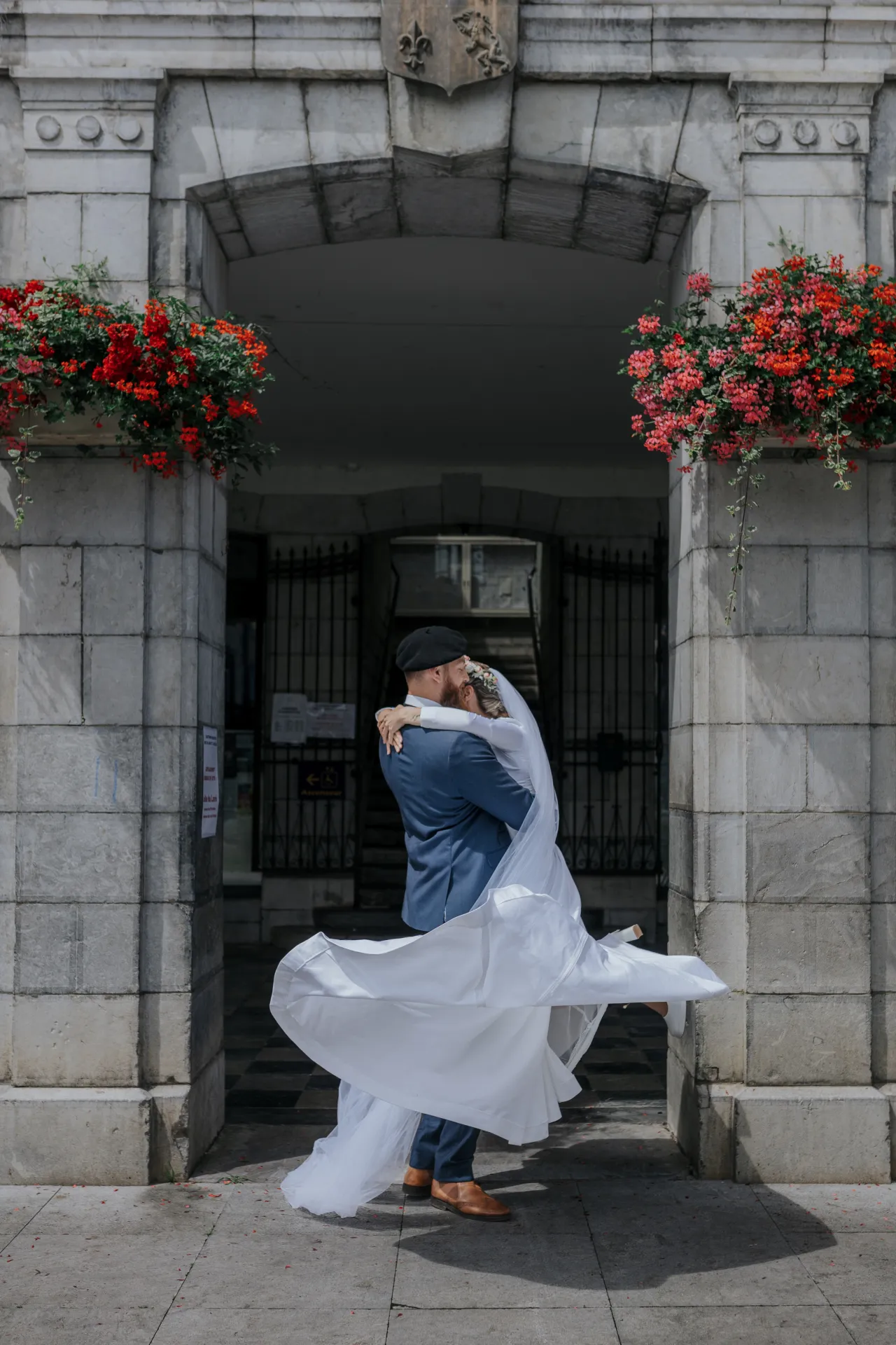Mariés s’enlaçant devant la mairie d’Arudy, robe en mouvement, lors d’un mariage intimiste dans les Pyrénées-Atlantiques