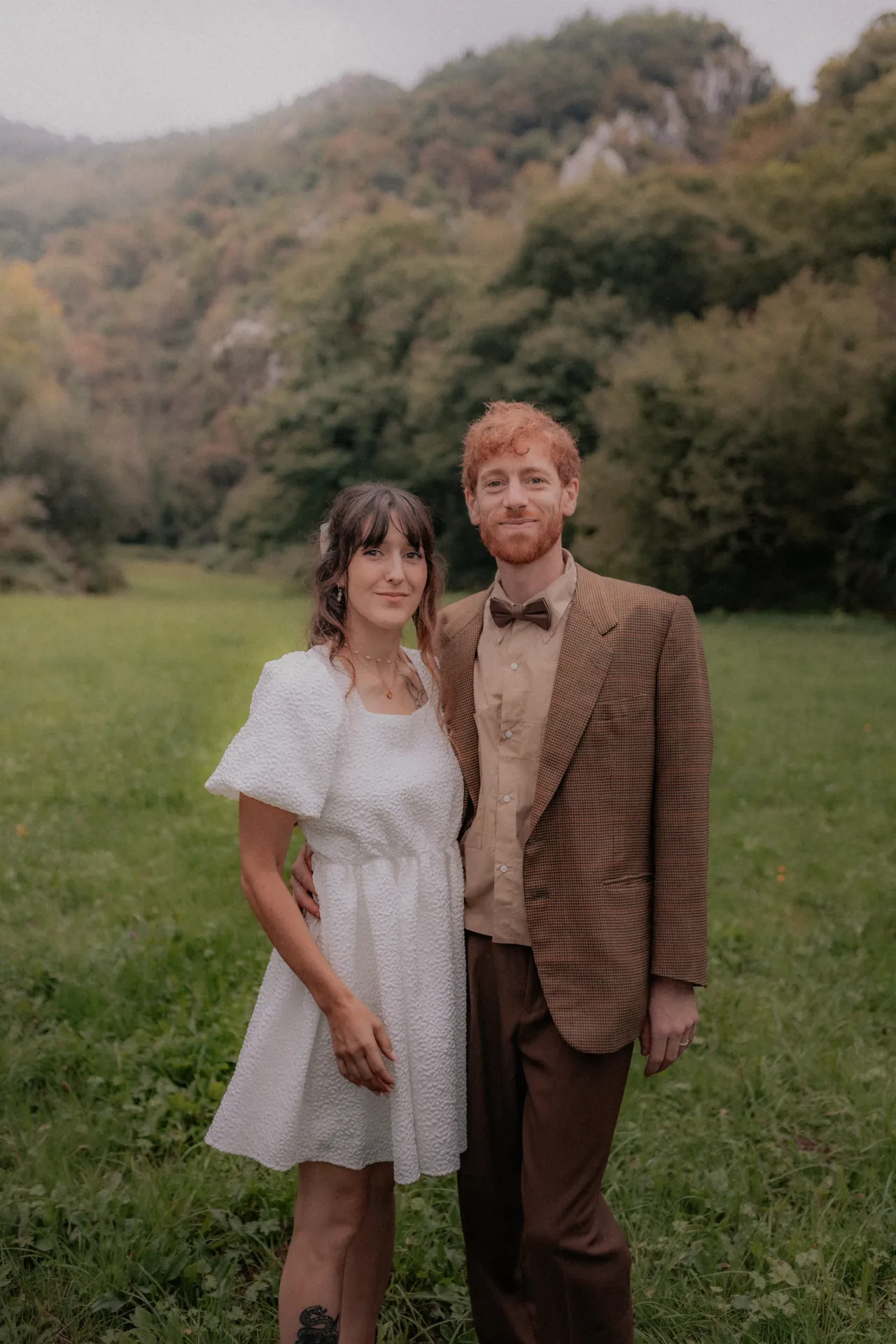 Couple de mariés au style vintage posant dans une prairie verdoyante près de Pau, entre élégance naturelle et douceur