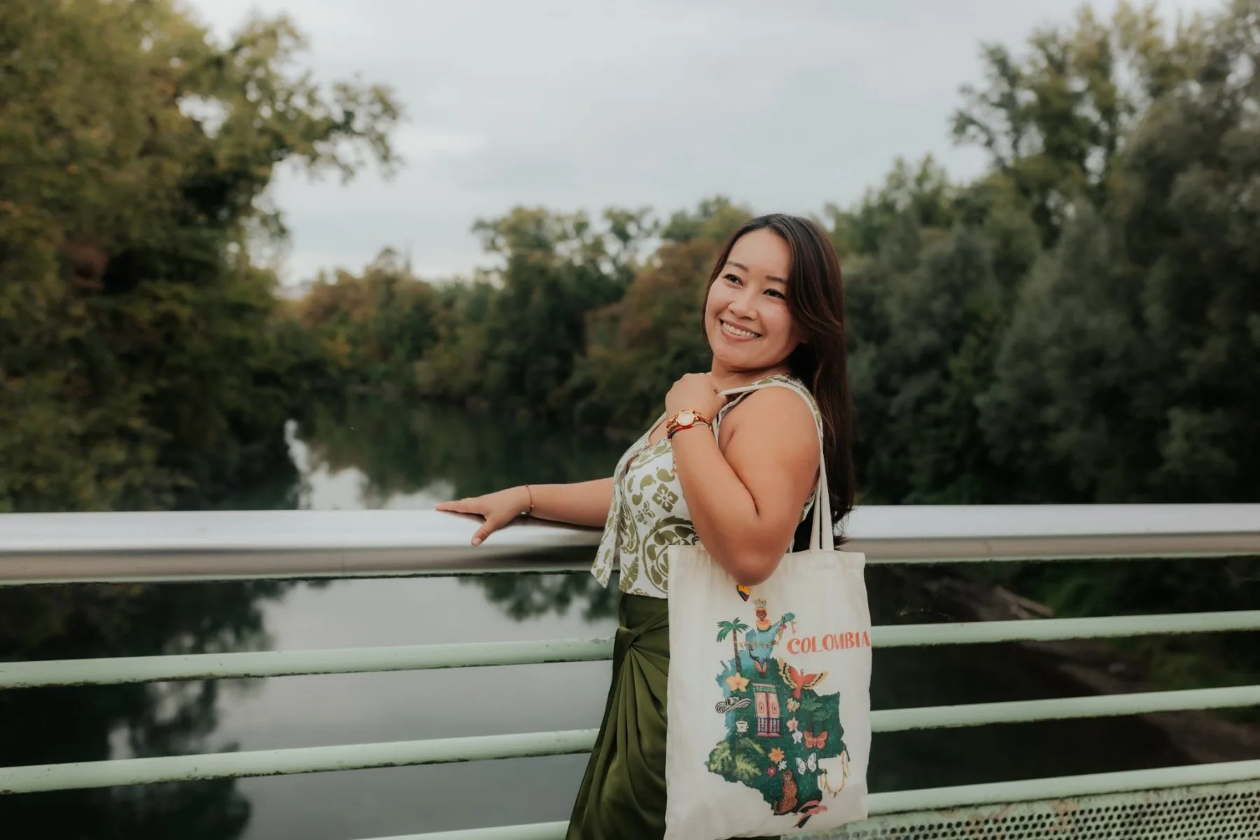 Portrait naturel d’une femme souriante sur un pont au bord de l’eau à Pau, ambiance douce pour une séance photo d’anniversaire en couple