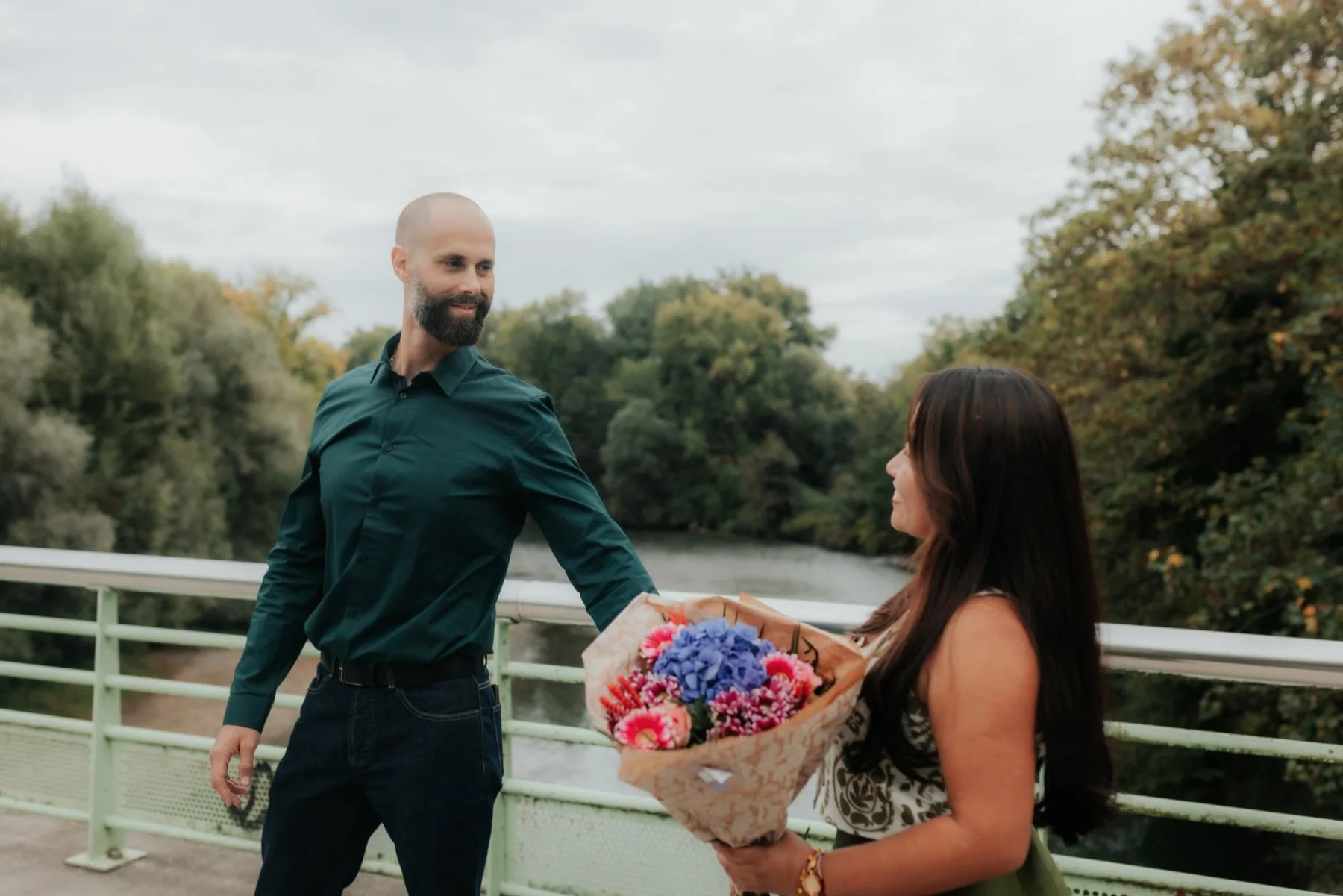 Couple en séance photo d’anniversaire à Pau, au Stade des eaux vives, avec bouquet de fleurs sur un pont