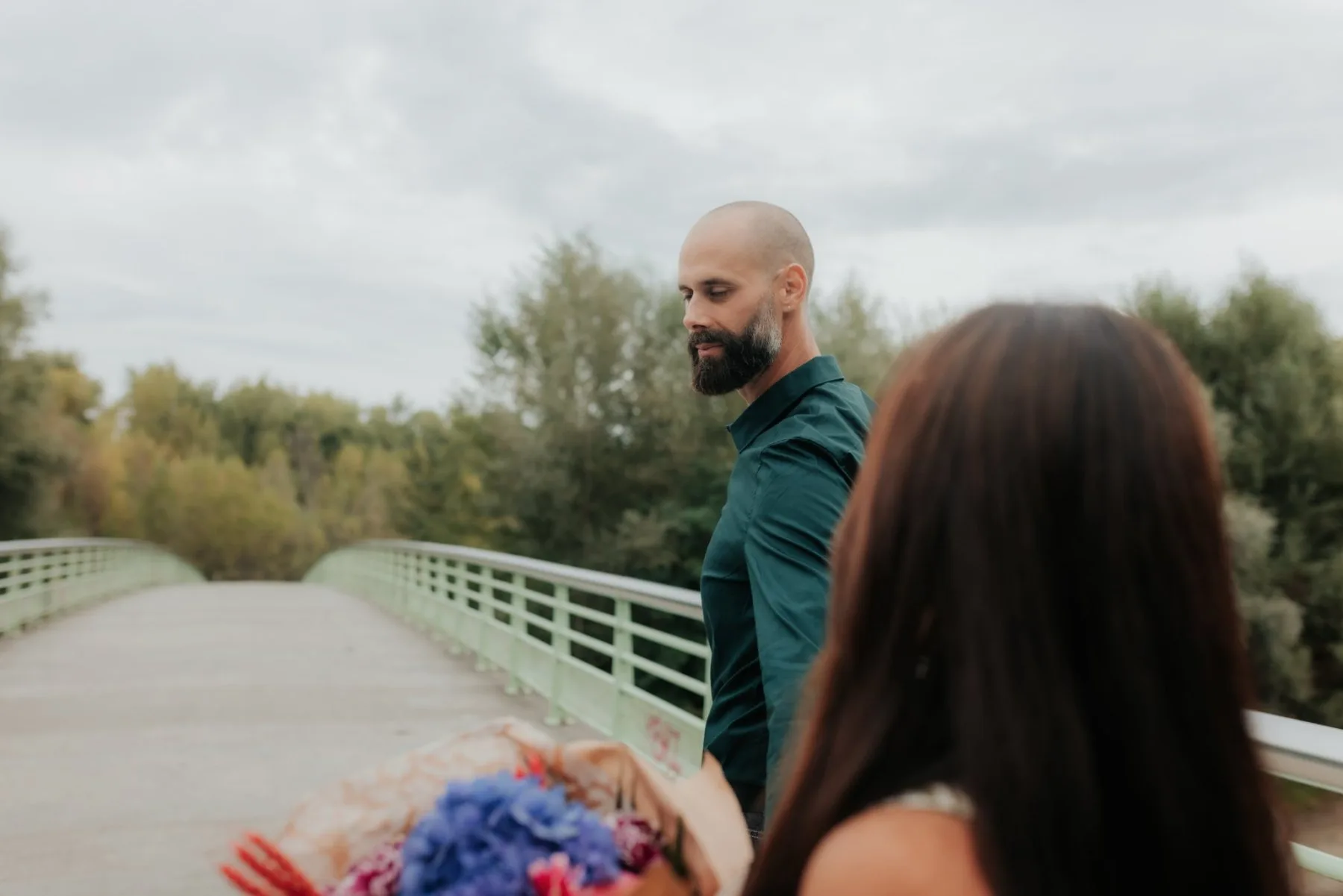 Couple en séance photo d’anniversaire à Pau sur une passerelle, bouquet en main, pour des images naturelles et authentiques