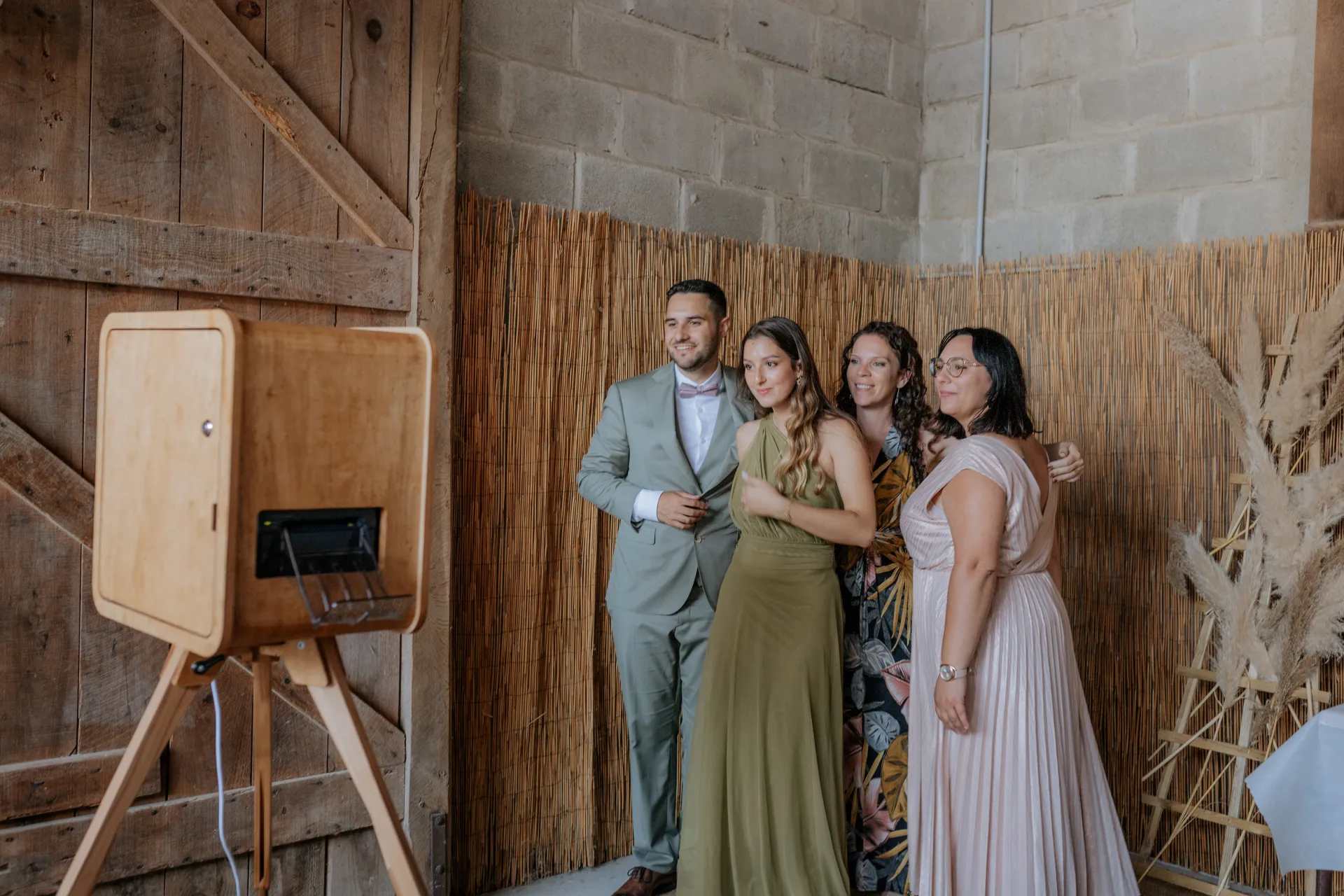Invités posant devant un photobooth de mariage à Pau dans une grange au décor bohème et champêtre