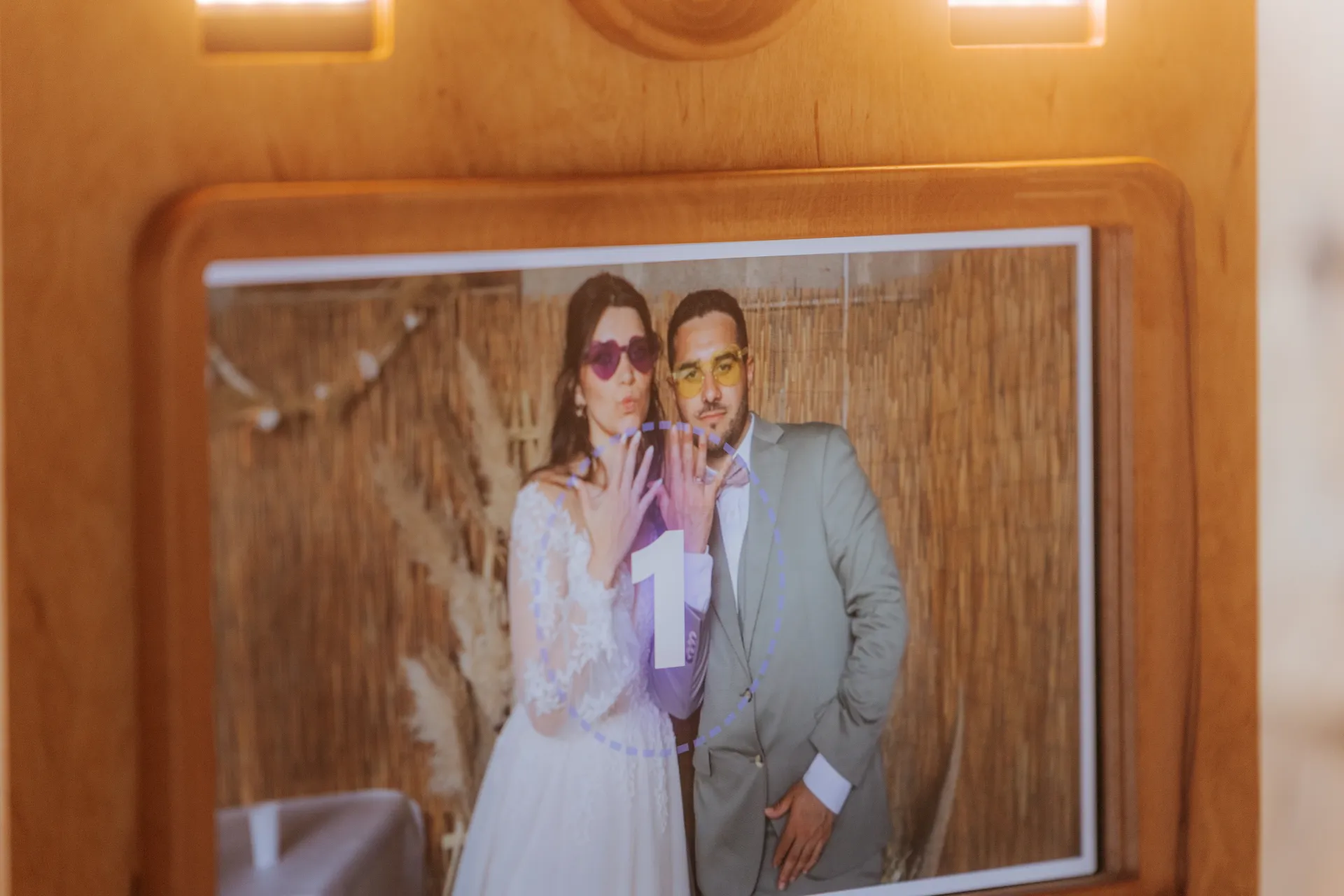 Mariés posant avec lunettes colorées dans un photobooth de mariage à Pau, ambiance festive et originale