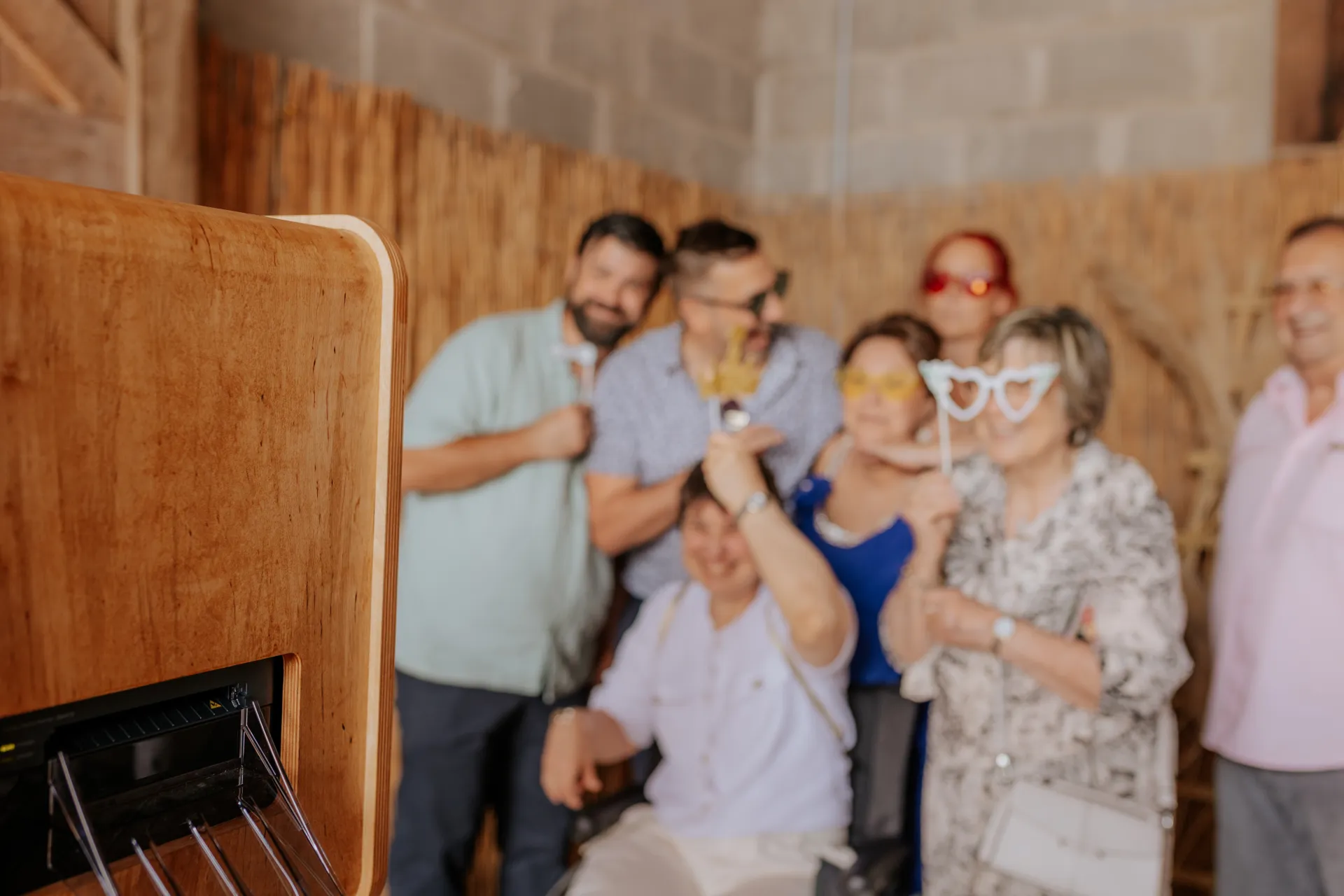 Invités posant devant un photobooth mariage en bois à Pau avec accessoires festifs et ambiance conviviale