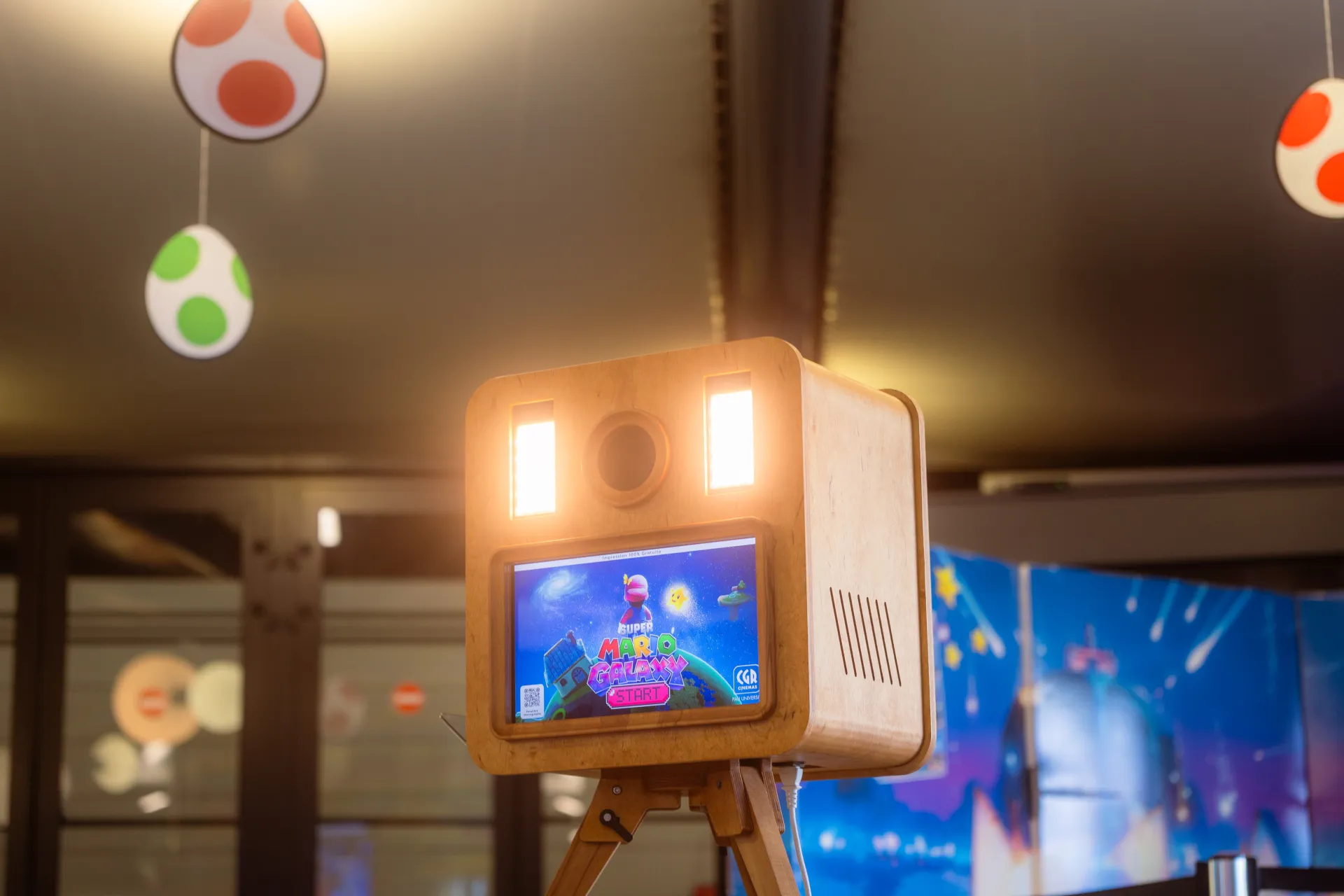 Photobooth en bois au CGR Pau Université décoré sur le thème Mario Galaxy avec œufs de Yoshi suspendus