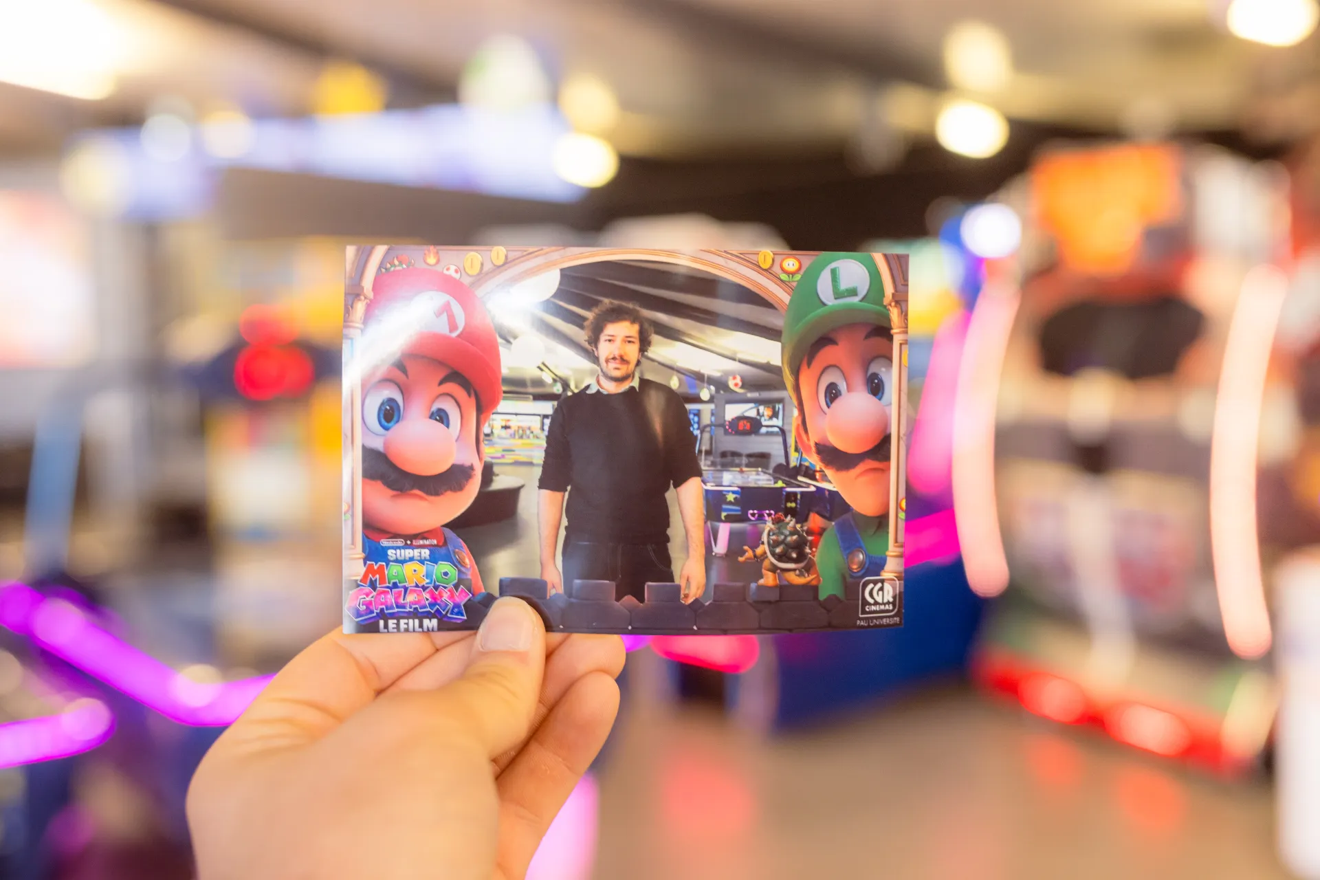 Tirage photobooth Mario Galaxy au CGR Pau Université, tenu en main devant les bornes d’arcade du cinéma