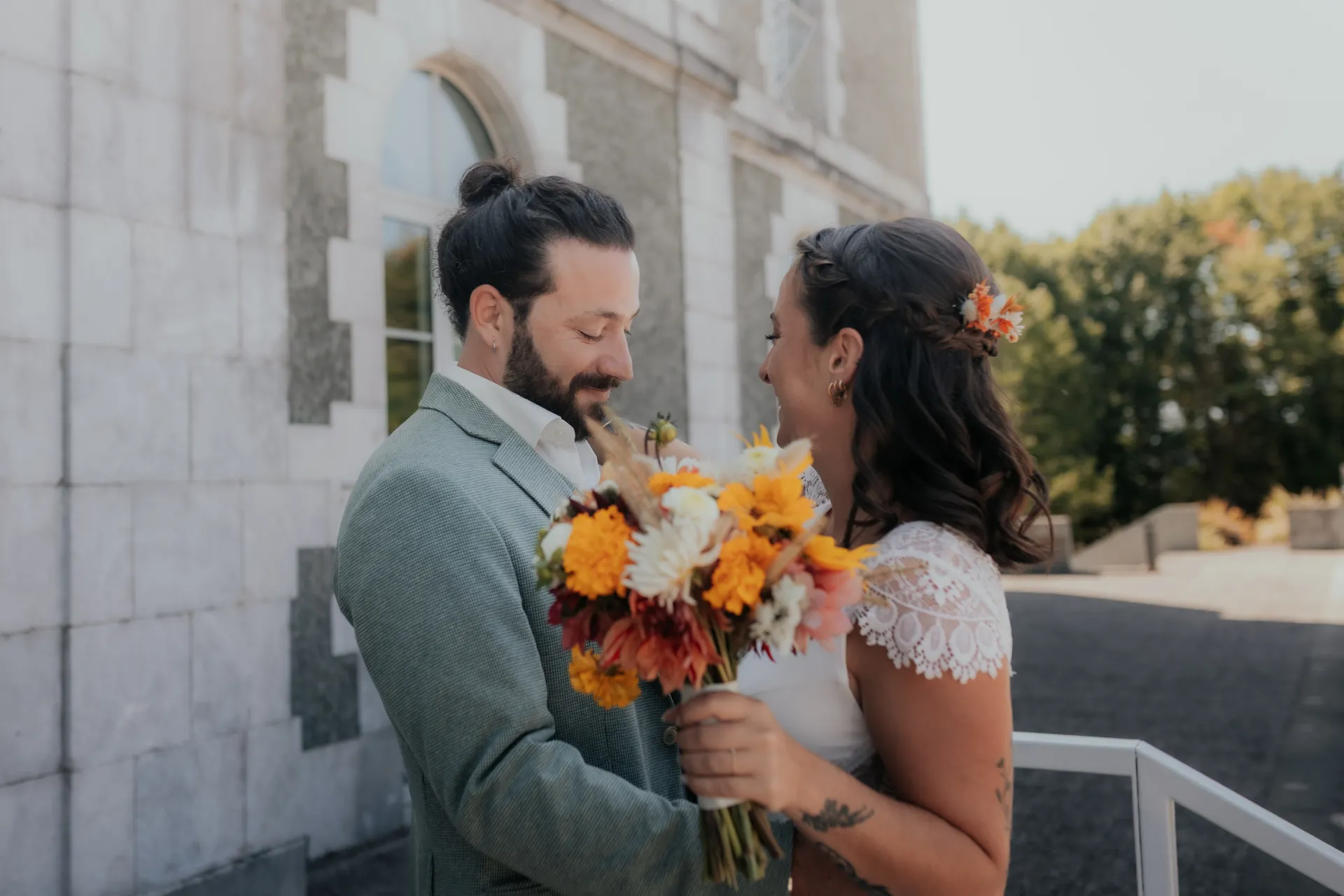 Couple de mariés devant un lieu de réception, bouquet en main, photo idéale pour illustrer la réservation d’un photographe de mariage