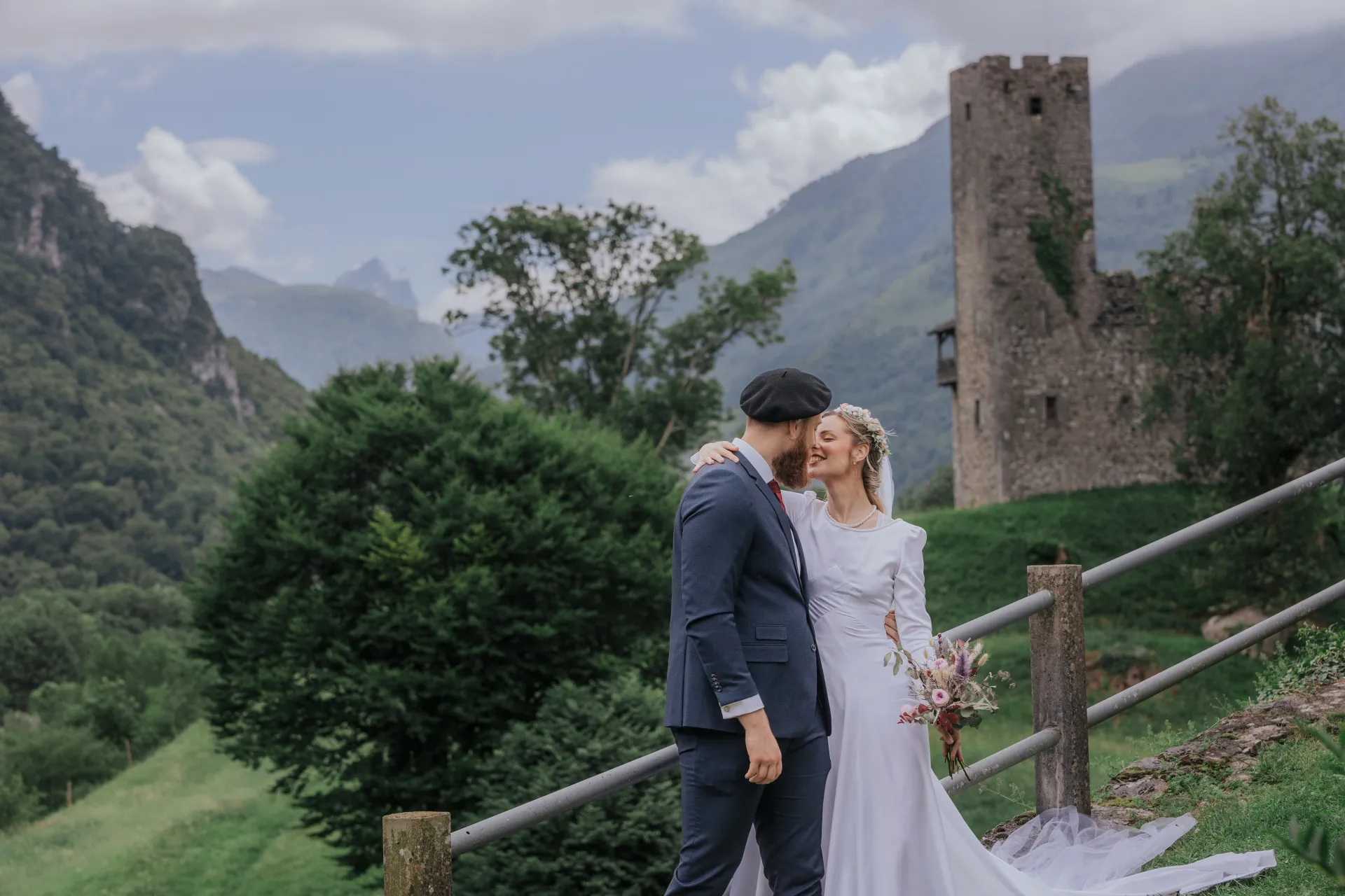 Mariés en séance couple à Castet devant l’Église Saint-Polycarpe, avec vue sur les montagnes des Pyrénées