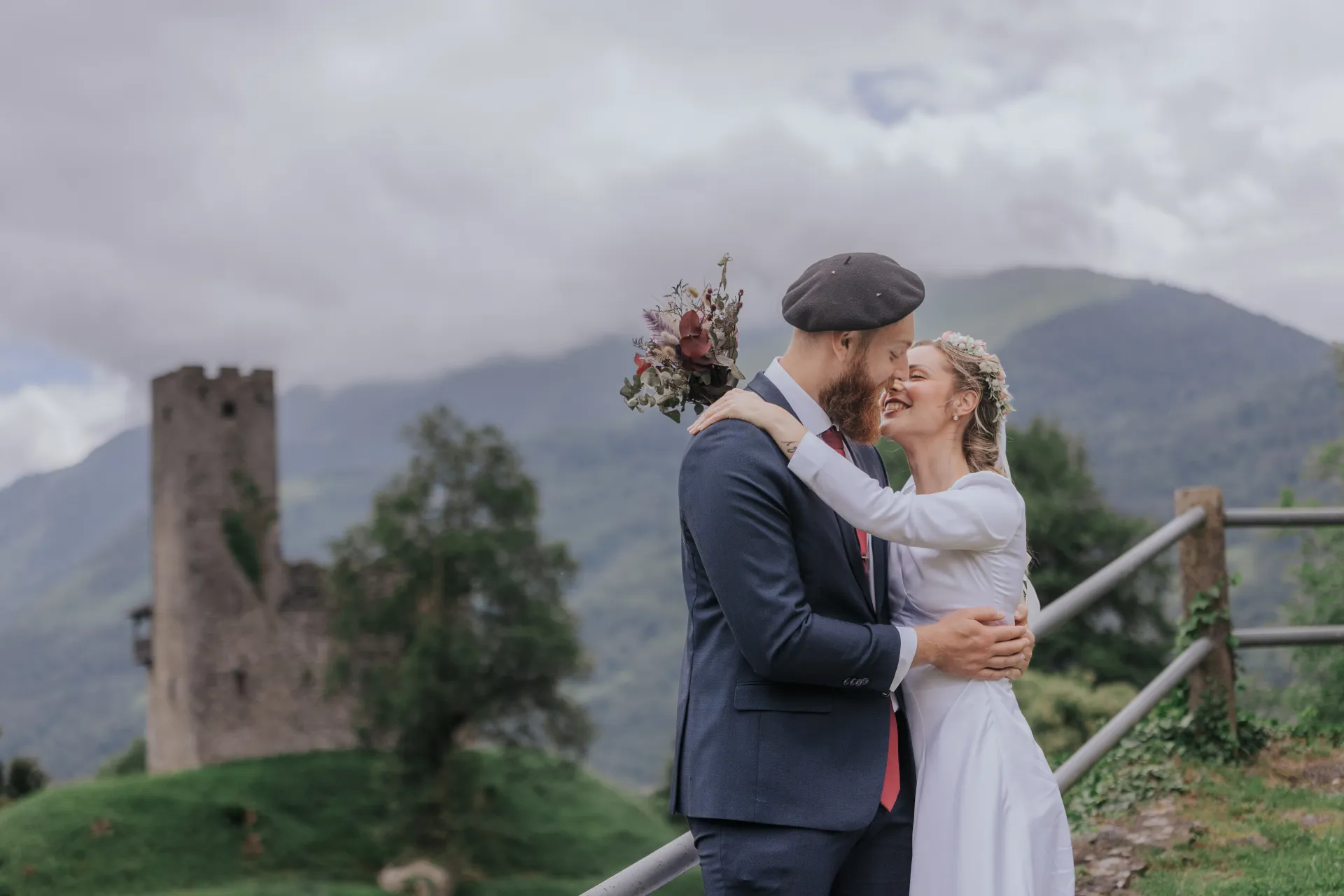 Couple de mariés enlacés à Castet devant les montagnes, près de l’Église Saint-Polycarpe, séance photo de mariage