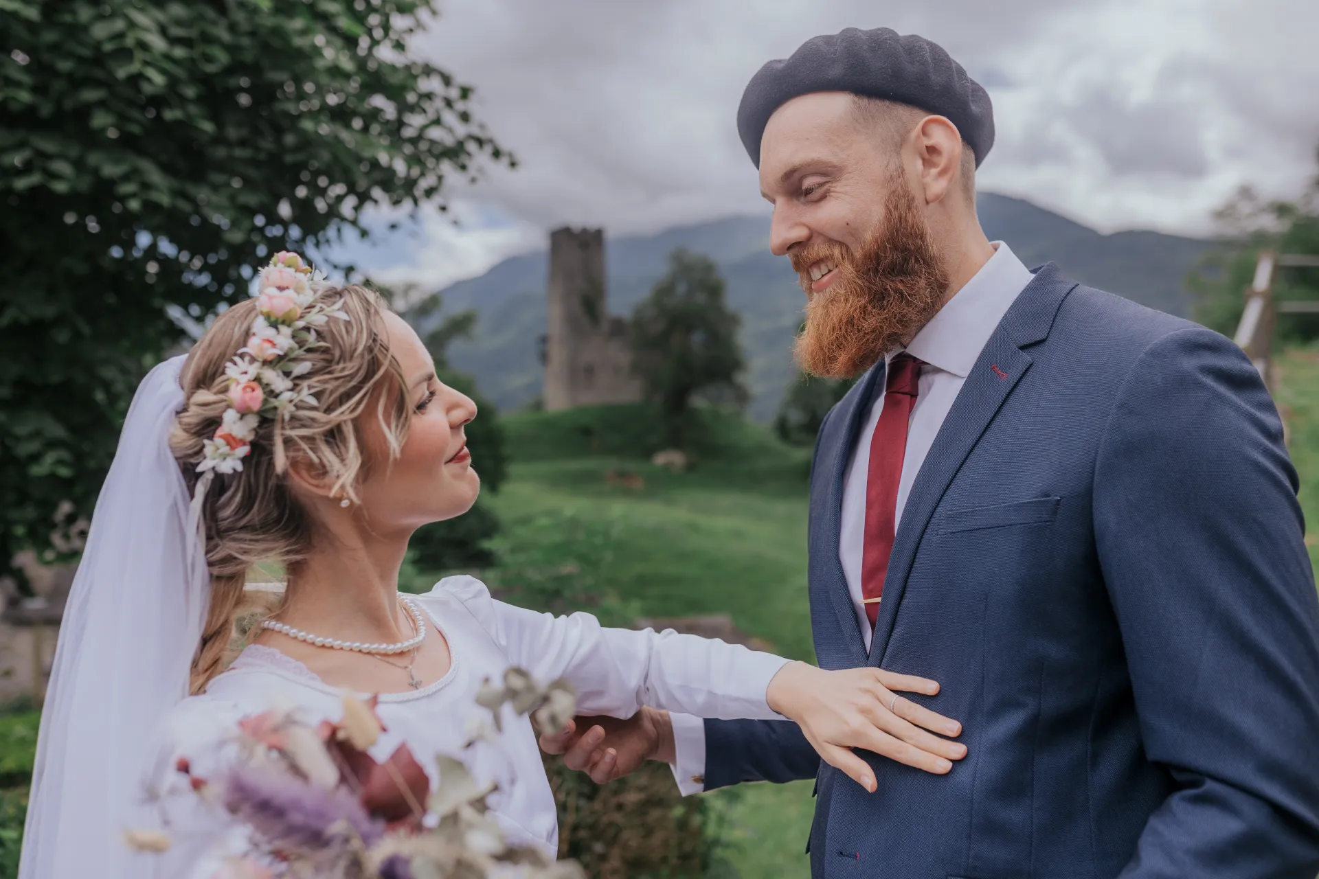 Mariés en séance couple à Castet près de l’église Saint-Polycarpe, regard complice et montagnes en arrière-plan