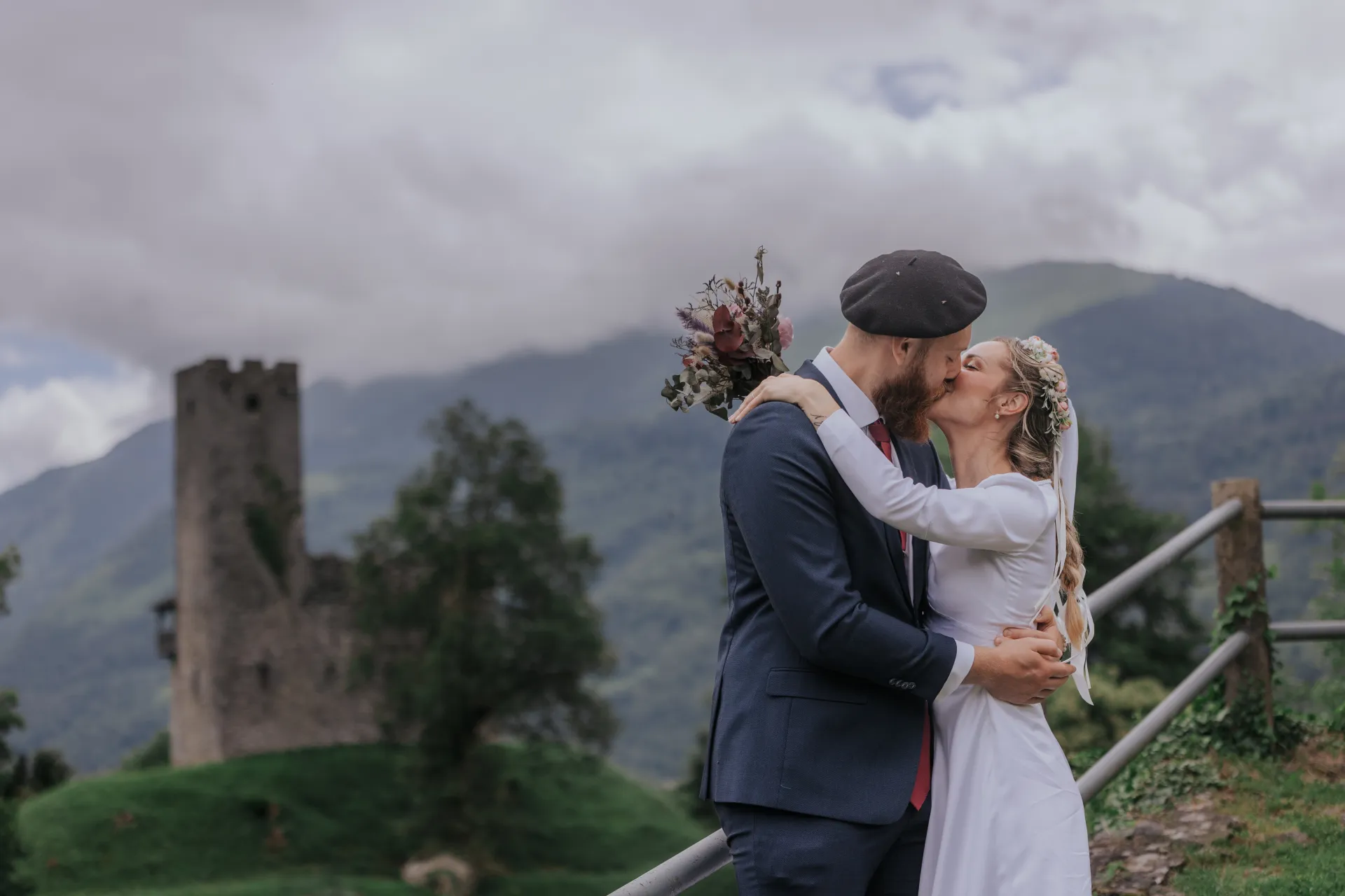 Mariés s’embrassant à Castet devant les montagnes, lors d’une séance couple près de l’Église Saint-Polycarpe