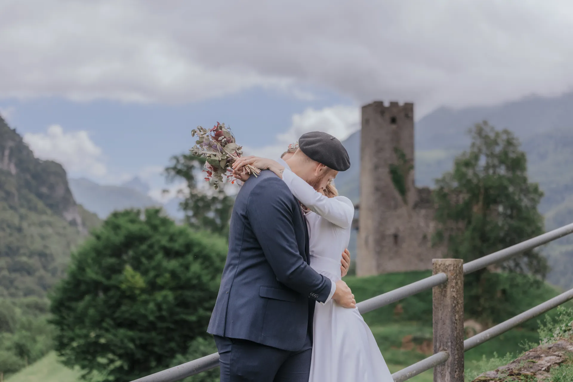 Mariés enlacés à Castet devant les ruines près de l’Église Saint-Polycarpe, séance couple au cœur des montagnes