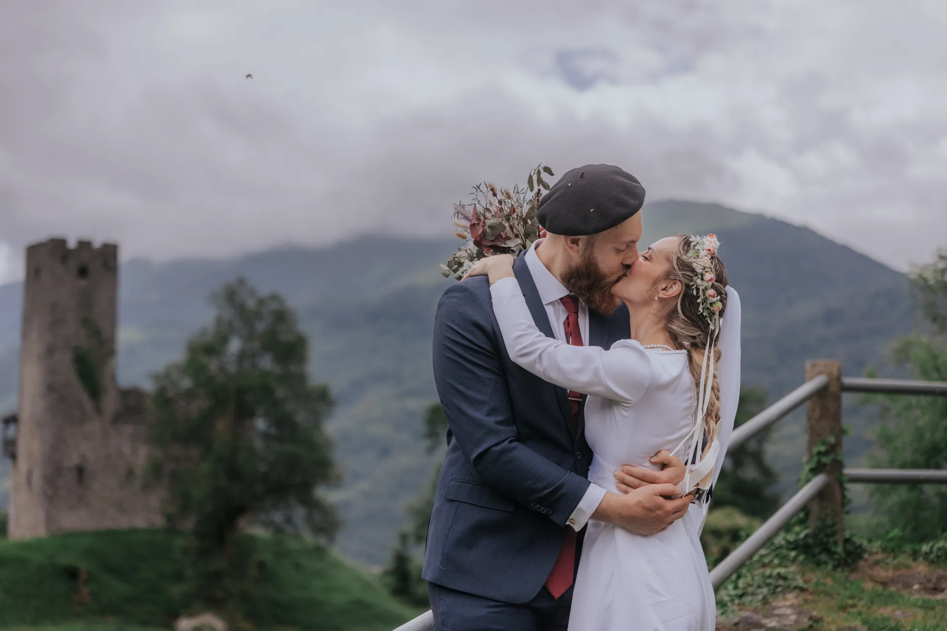 Mariés s’embrassant à Castet devant les montagnes, lors d’une séance couple près de l’Église Saint-Polycarpe