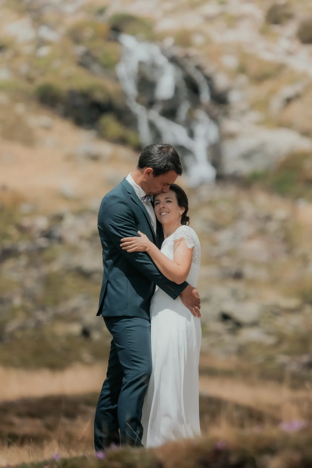 Couple de mariés enlacé aux Lacs d’Ayous, séance Day After en montagne avec cascade, Pyrénées-Atlantiques