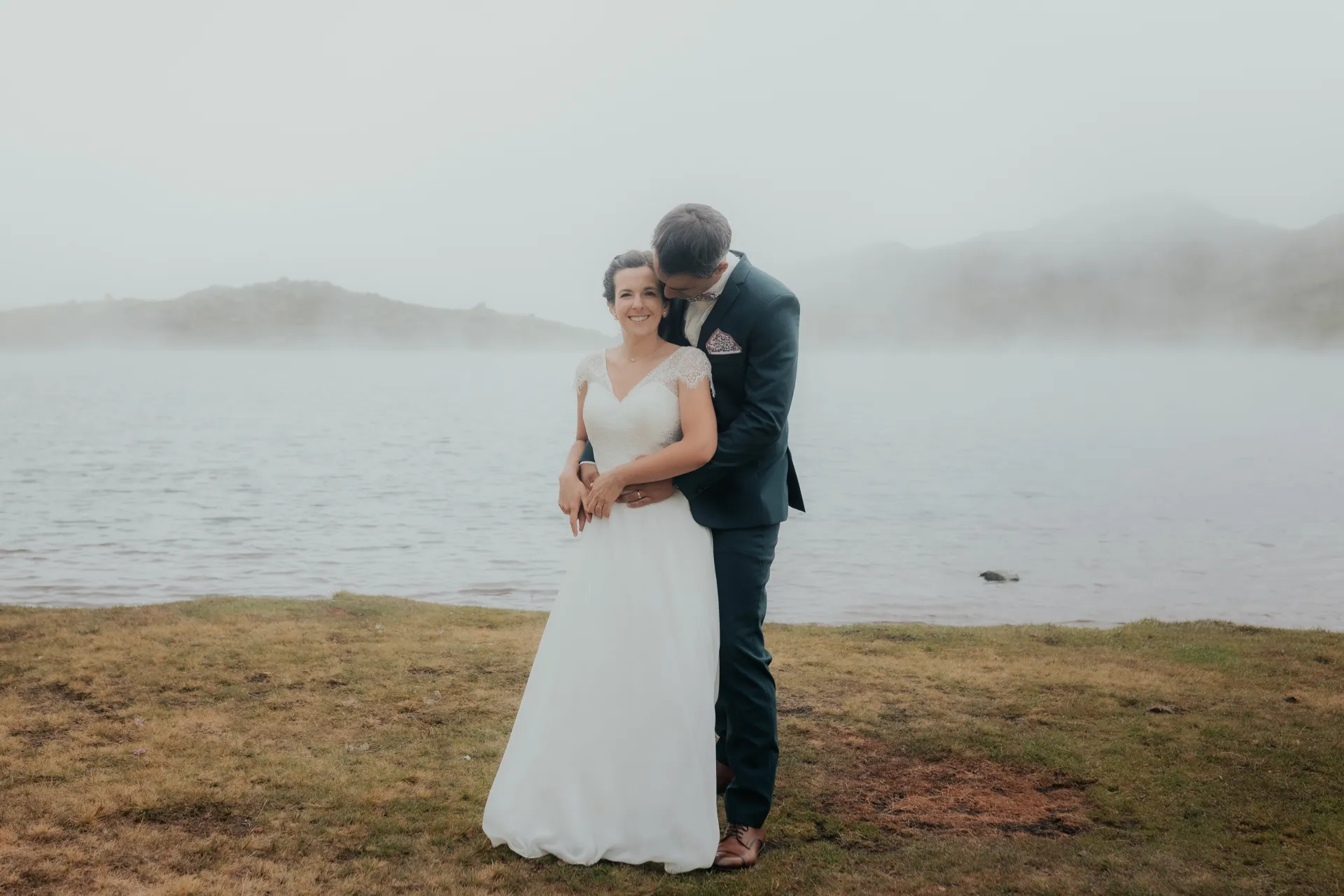 Couple de mariés enlacés au bord d’un lac brumeux aux Lacs d’Ayous, séance Day After dans les Pyrénées-Atlantiques