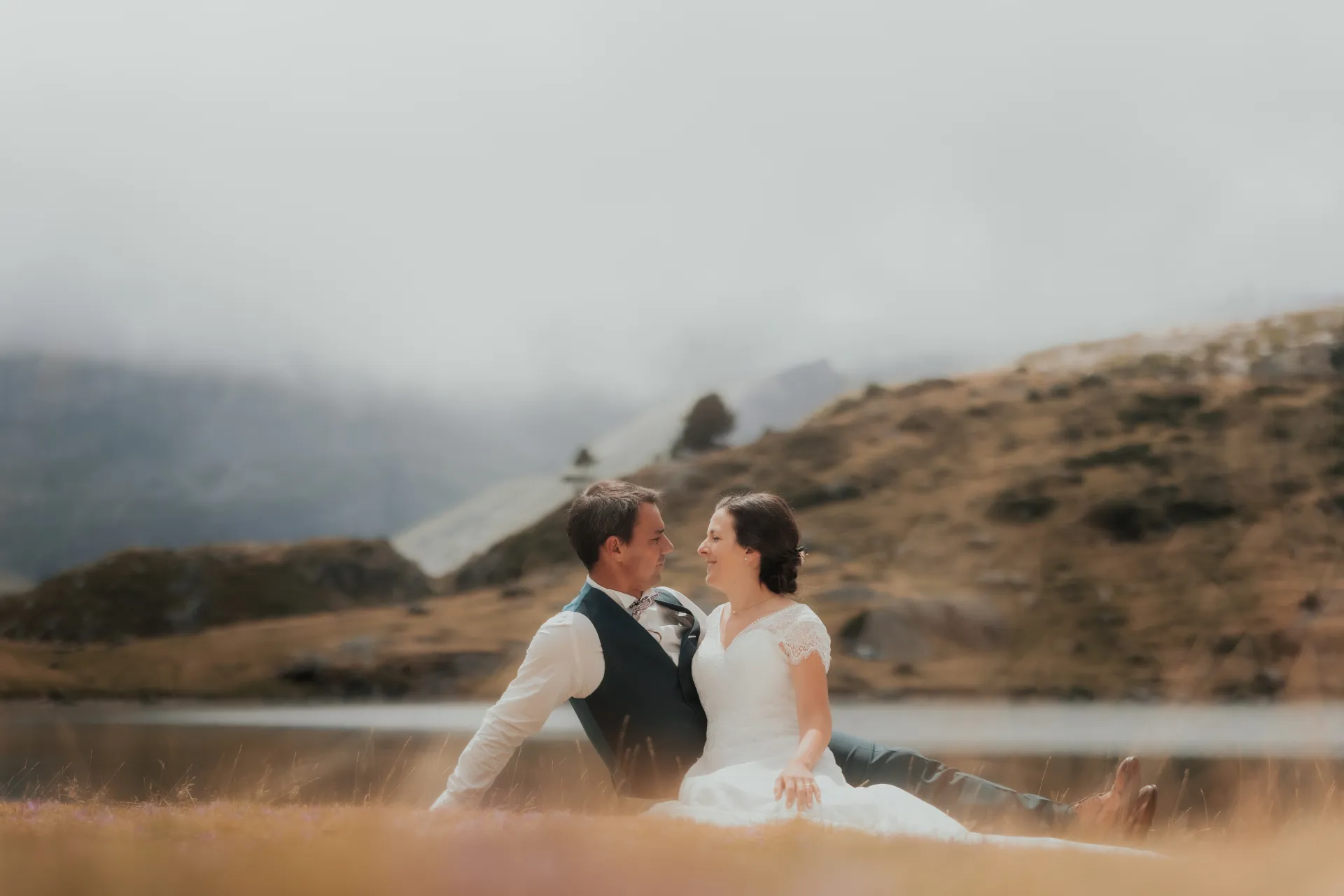 Couple de mariés assis face à face aux Lacs d’Ayous, séance day after en montagne dans les Pyrénées-Atlantiques
