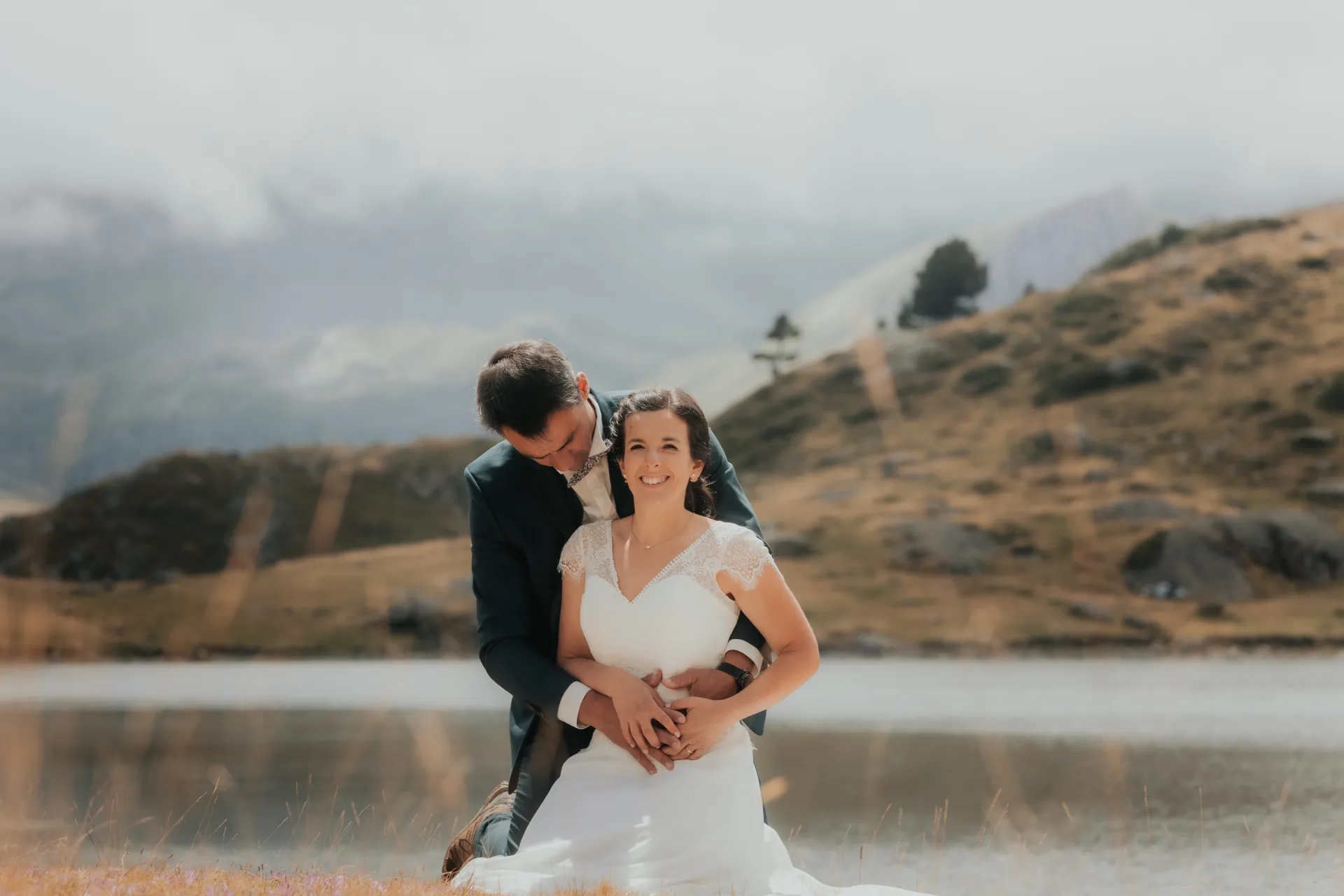 Couple de mariés enlacés au bord d’un lac aux Lacs d’Ayous, séance Day After en montagne dans les Pyrénées-Atlantiques