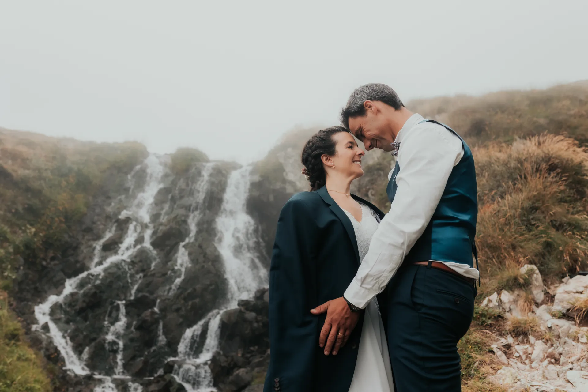 Couple de mariés en séance Day After devant une cascade aux Lacs d’Ayous, en montagne dans les Pyrénées-Atlantiques
