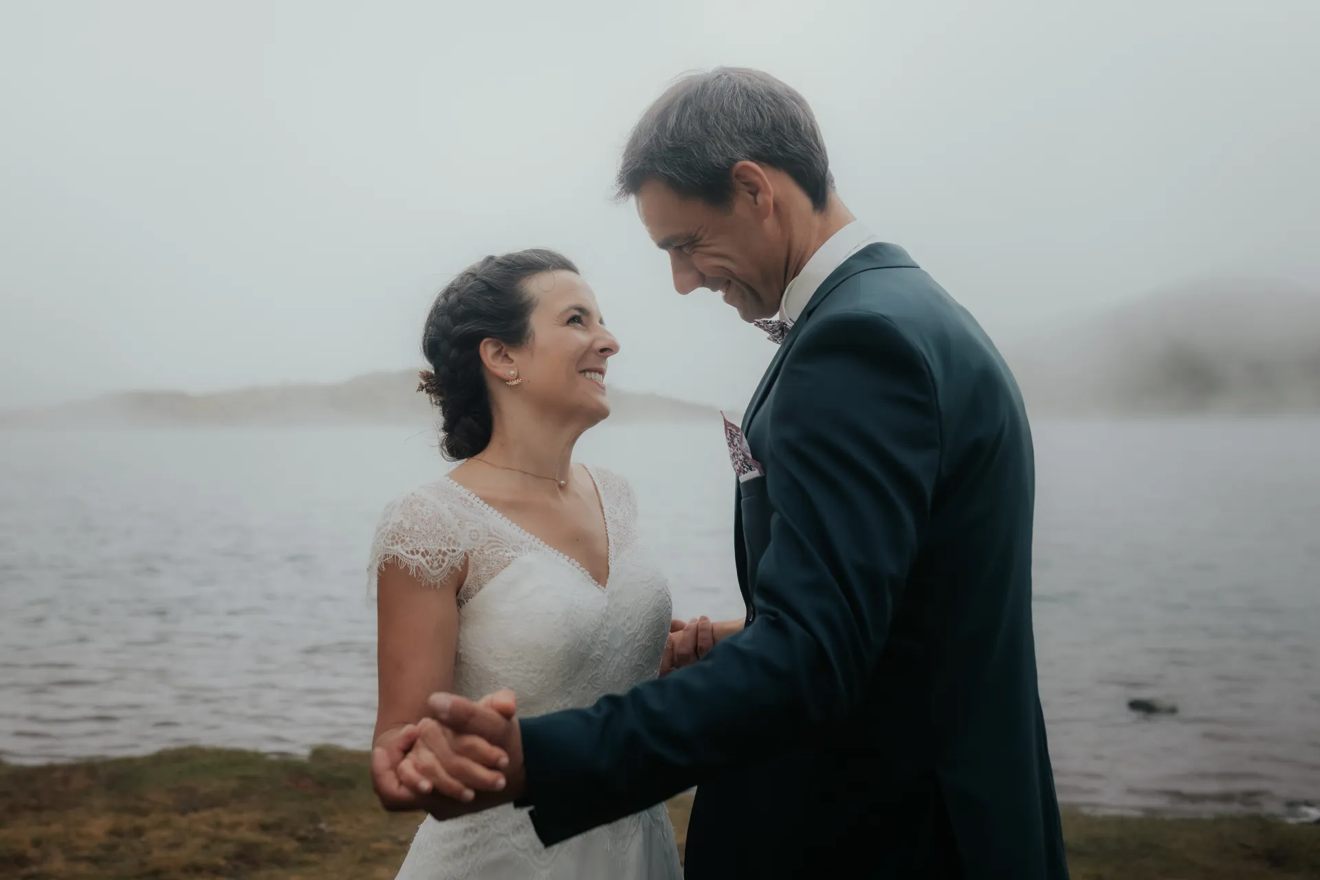 Couple de mariés souriant au bord d’un lac aux Lacs d’Ayous, séance Day After en montagne dans les Pyrénées-Atlantiques