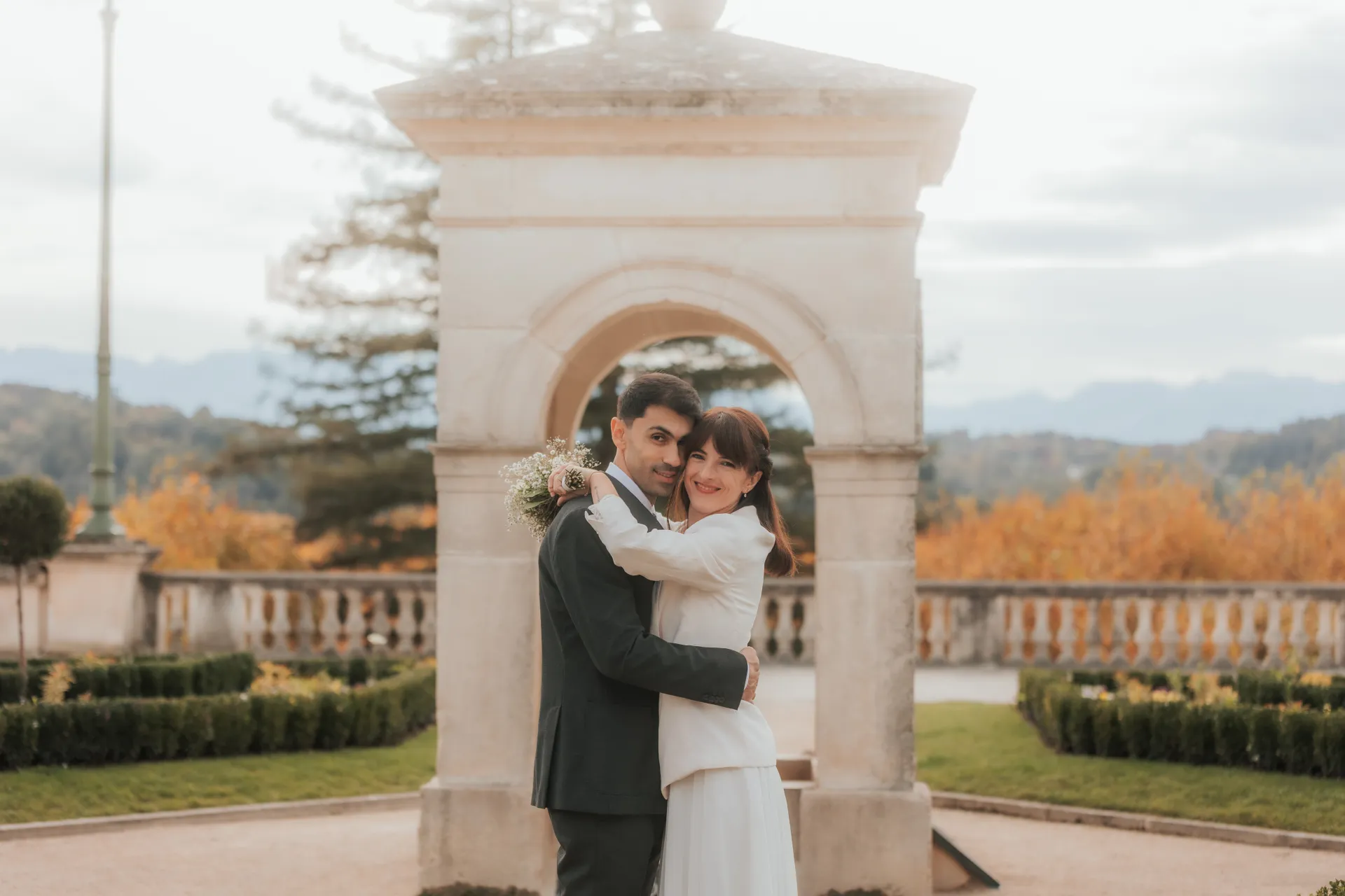 Couple de mariés enlacés sous une arche au Boulevard des Pyrénées à Pau, lors d’une séance photo mariage