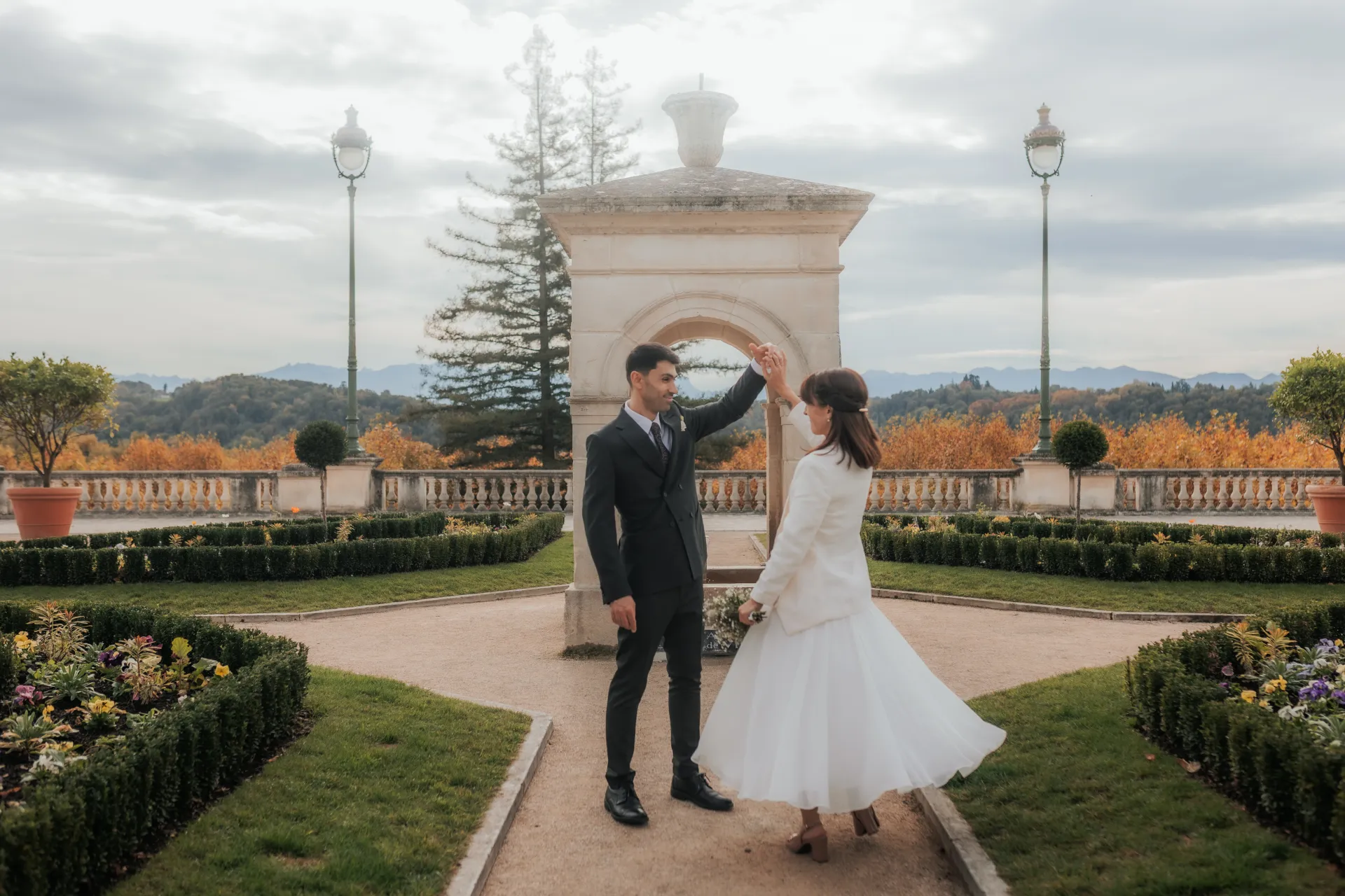 Couple de mariés dansant dans un jardin avec vue sur les Pyrénées, séance photo mariage à Pau