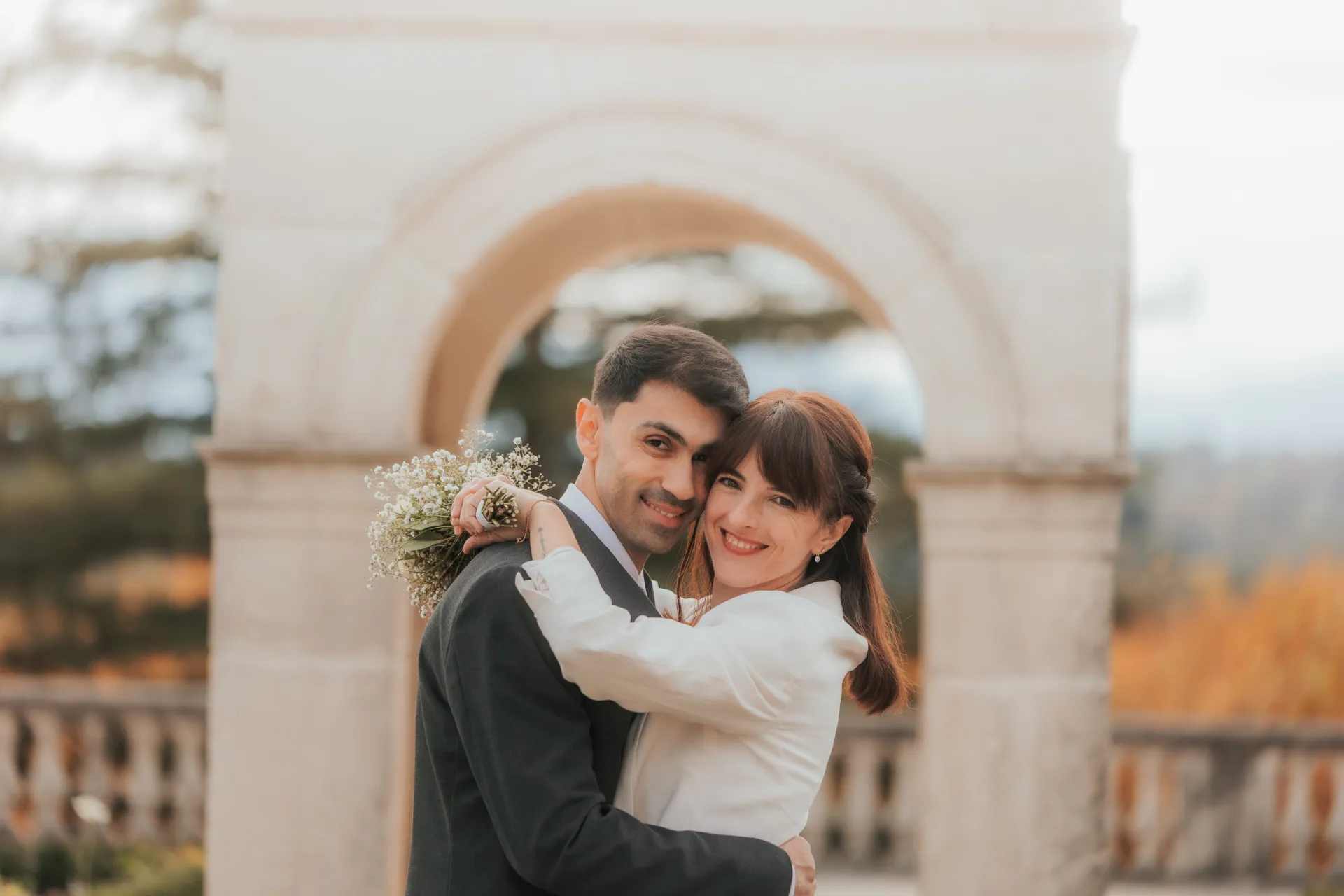 Couple de mariés enlacés sous une arche sur le Boulevard des Pyrénées à Pau, séance photo mariage romantique