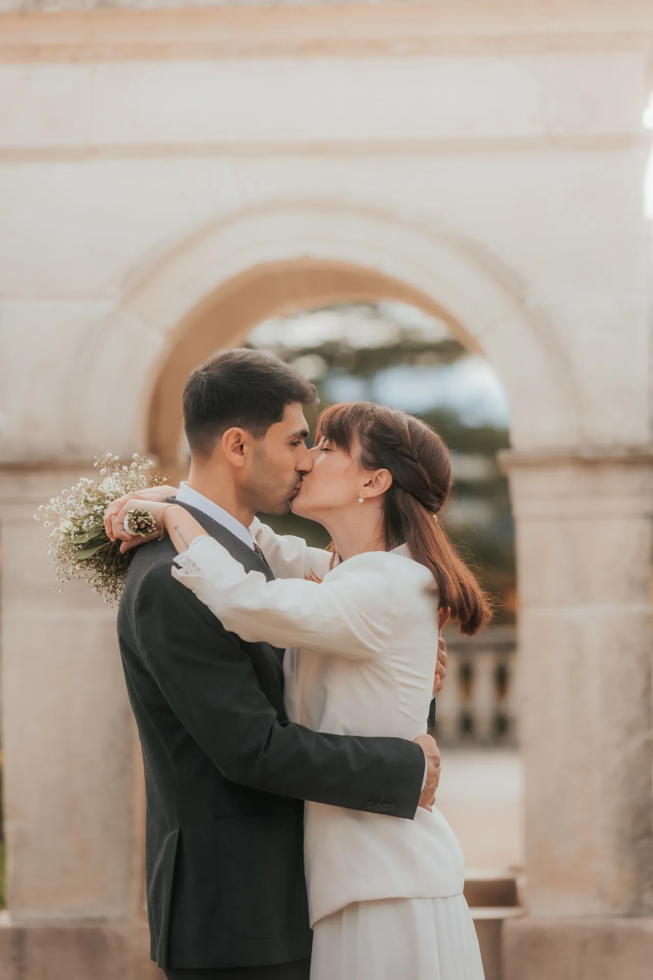 Couple de mariés s’embrassant sous une arche au Boulevard des Pyrénées à Pau lors d’une séance photo mariage