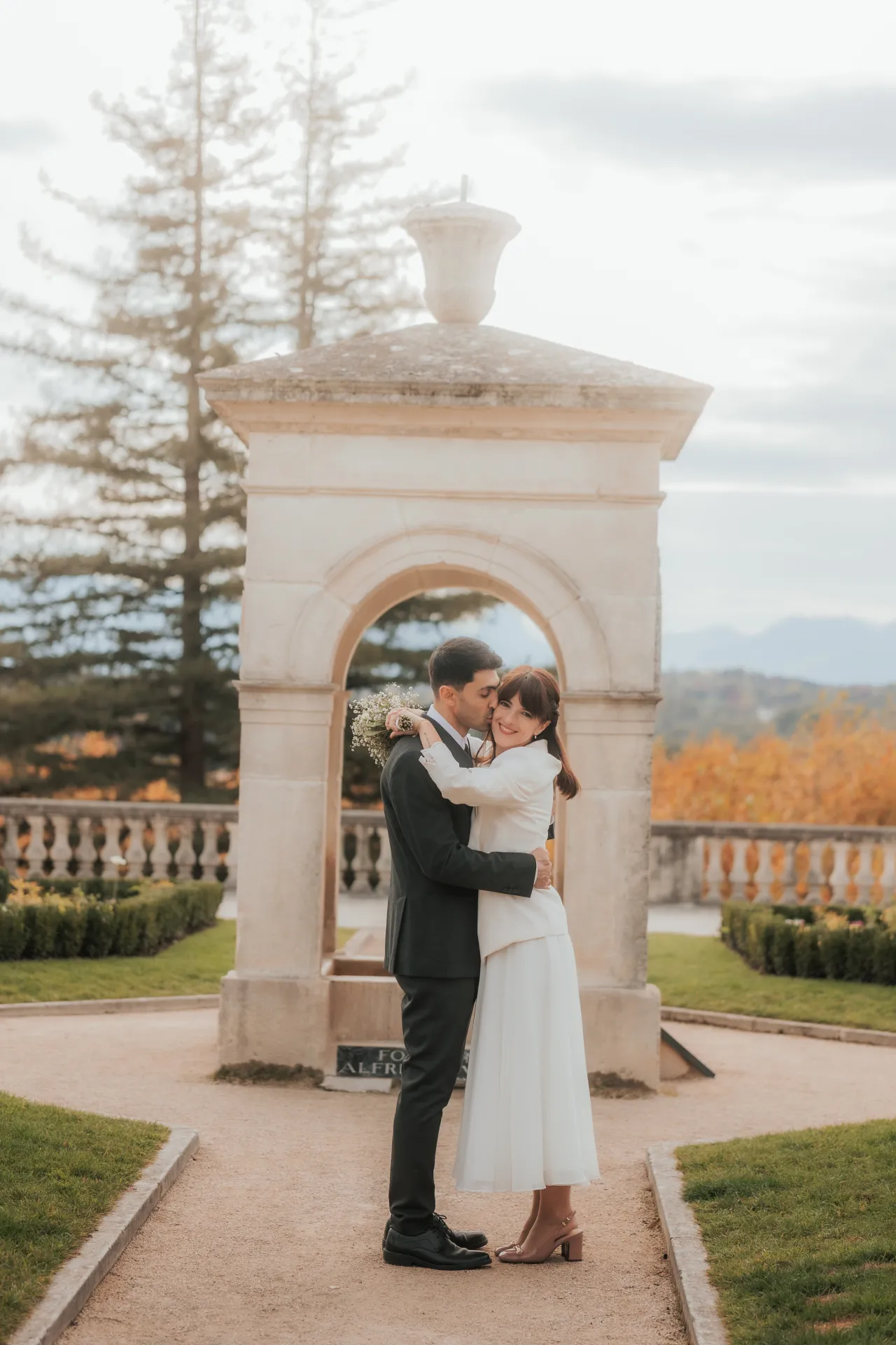 Couple de mariés enlacés sous une arche au Boulevard des Pyrénées à Pau, lors d’une séance photo mariage romantique