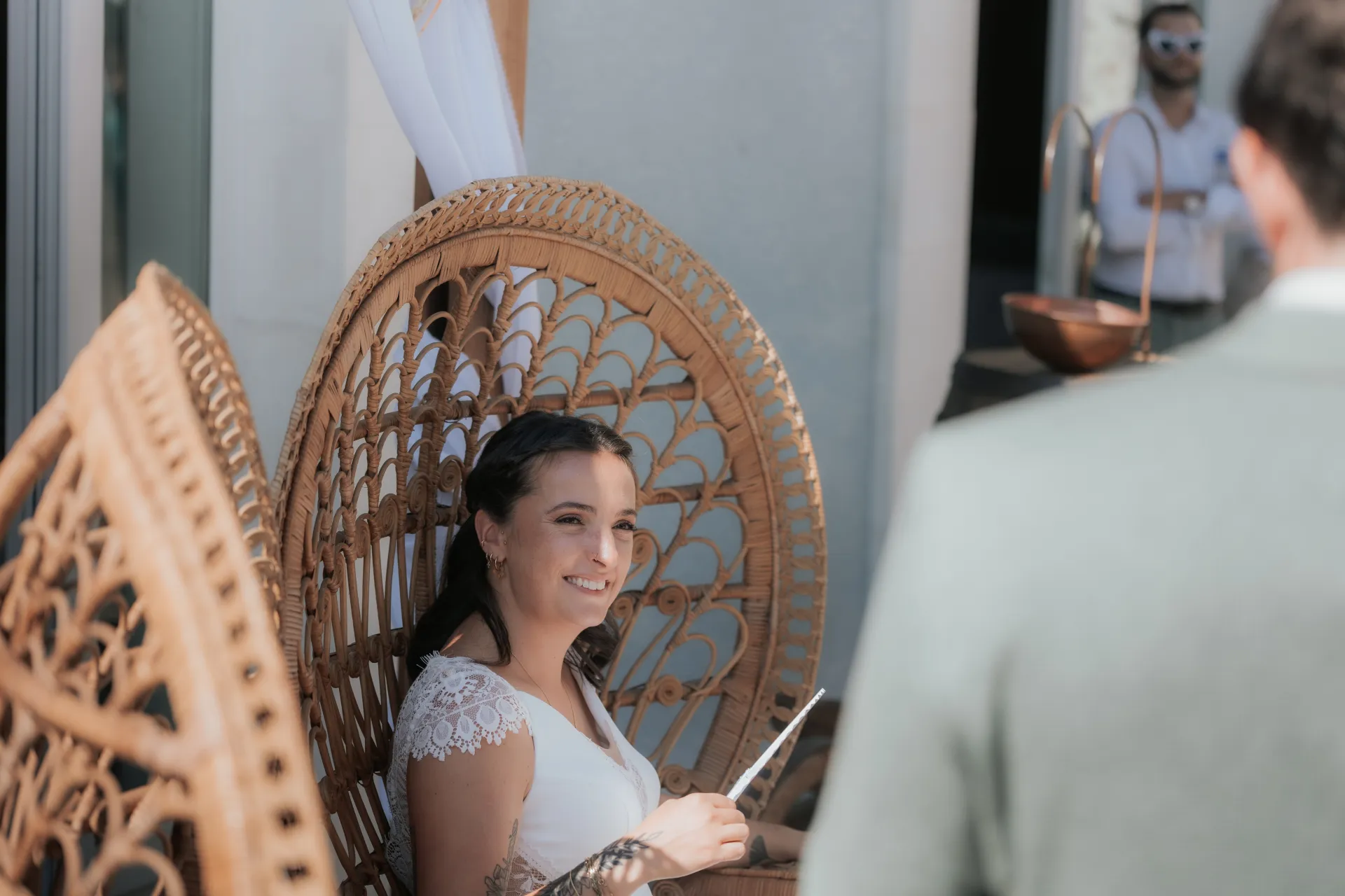 Mariée souriante assise dans un fauteuil en rotin à la Villa des 7 Moulins à Lescar, décor lumineux pour photos de mariage