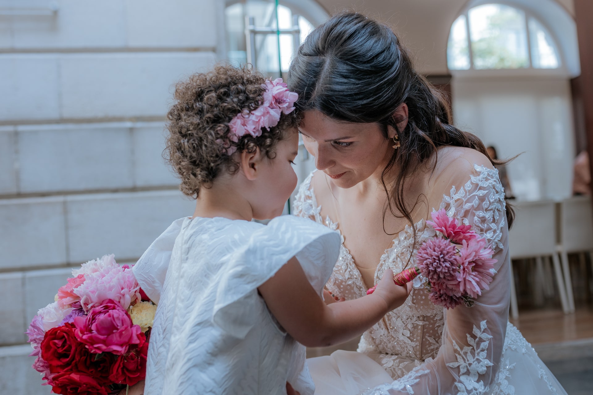 Mariée partageant un doux moment avec une petite fille tenant un bouquet, lors d'un mariage au Domaine de Bourdale-Dufau.