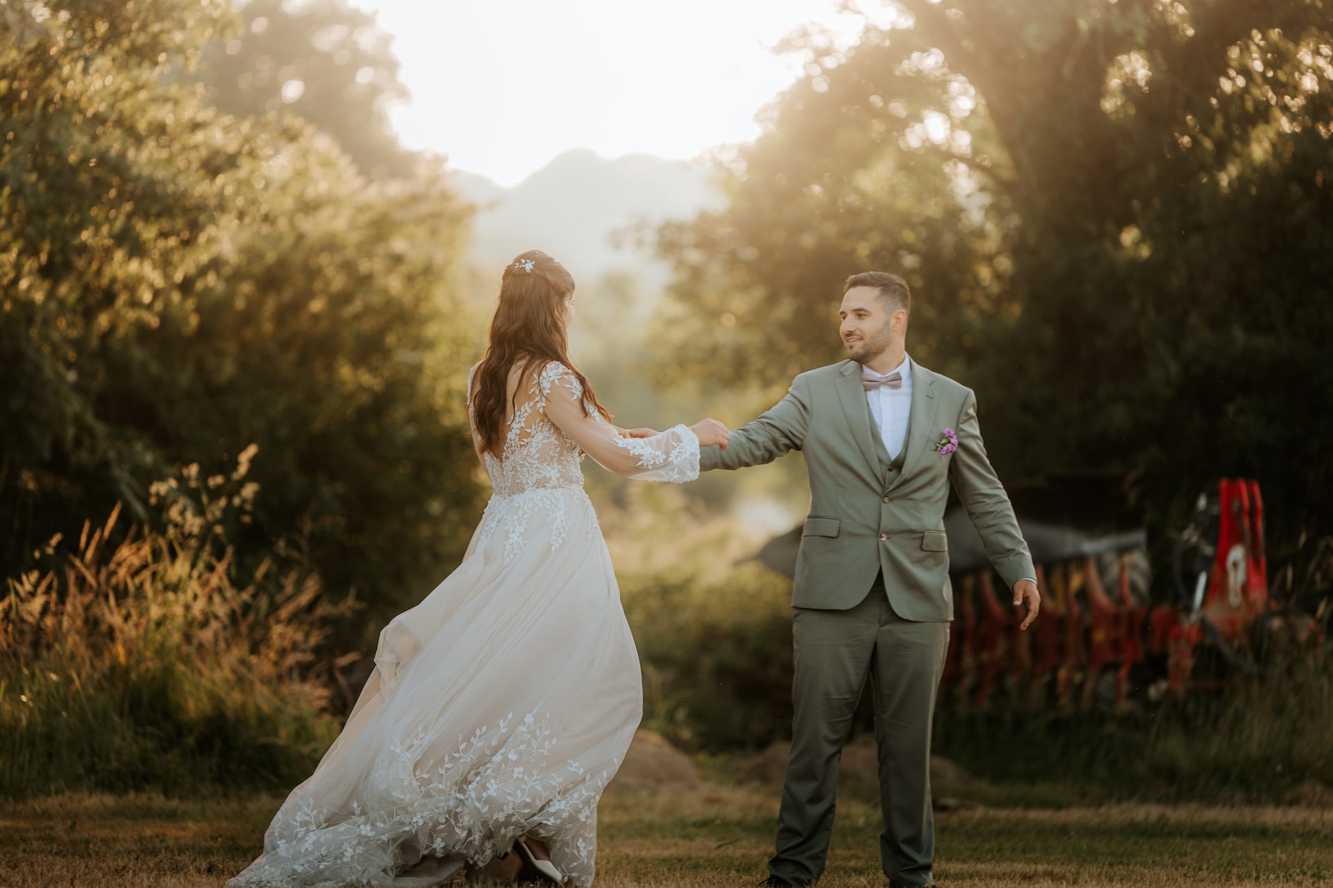 Mariés dansant dans un jardin ensoleillé, elle en robe élégante, lui en costume gris, ambiance romantique au Domaine de Bourdale-Dufau.