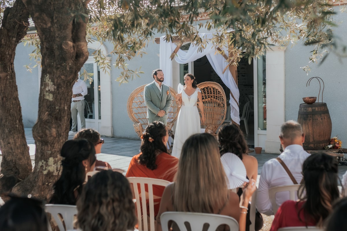 Mariage en plein air à la Villa des 7 Moulins, les mariés échangent leurs vœux devant les invités sous une arche décorée, le 23 août 2025.