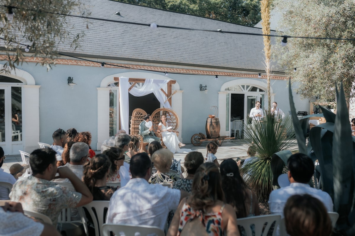 Cérémonie de mariage en extérieur à la Villa des 7 Moulins, invités attentifs et mariés sous une pergola décorée.