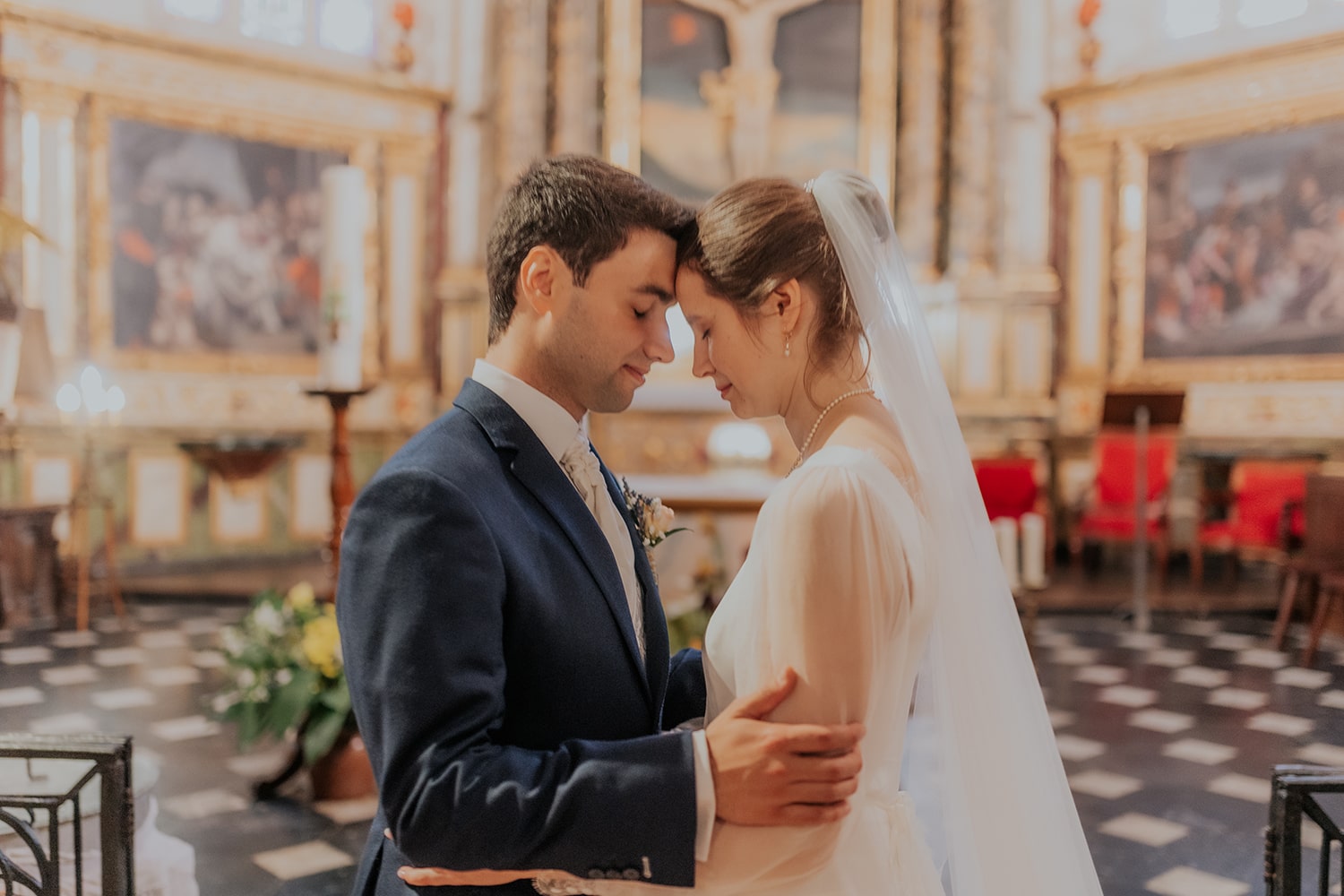 Les mariés se tiennent l'un et l'autre, les yeux fermés dans l'église - Photographe mariage pau