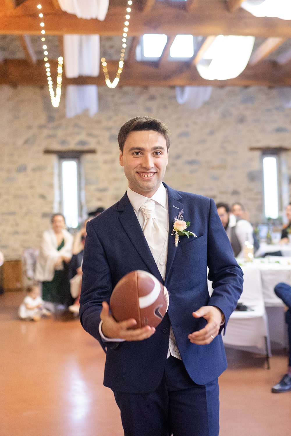 Photographie du marié qui tient un ballon de rugby dans les mains le jour de son mariage. - Photographe Mariage Pau